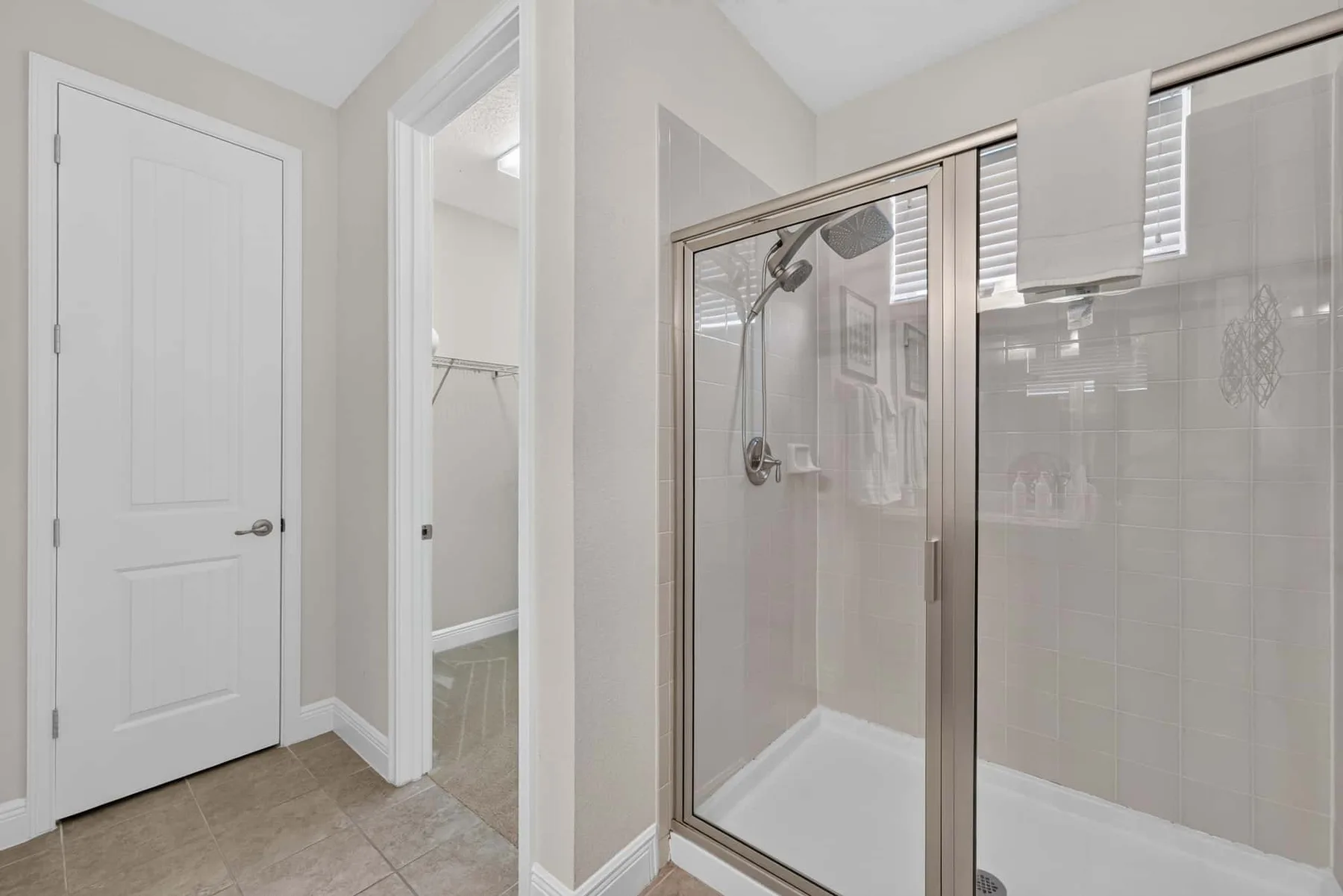A bathroom with a glass-enclosed shower and a white door.