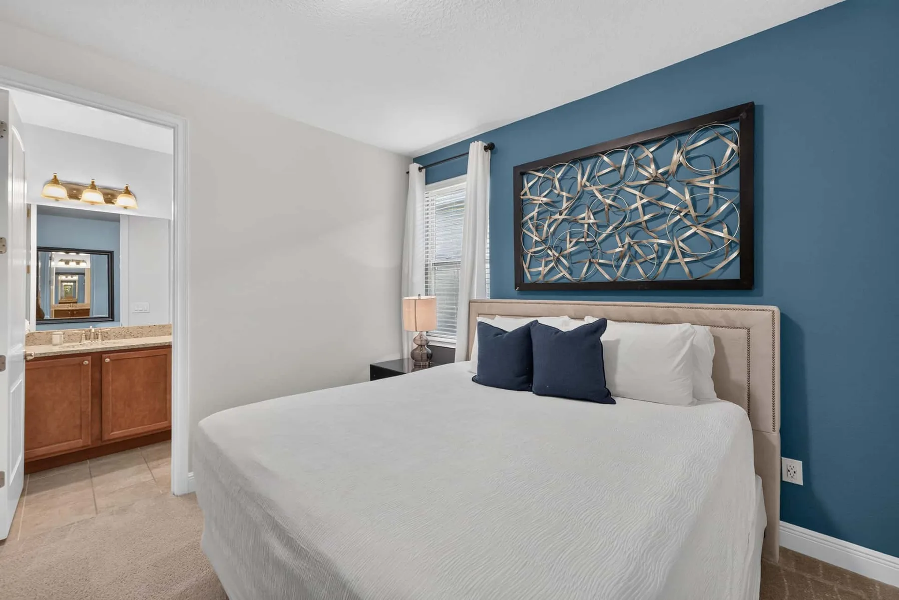 A bedroom with a neatly made bed and a blue accent wall.