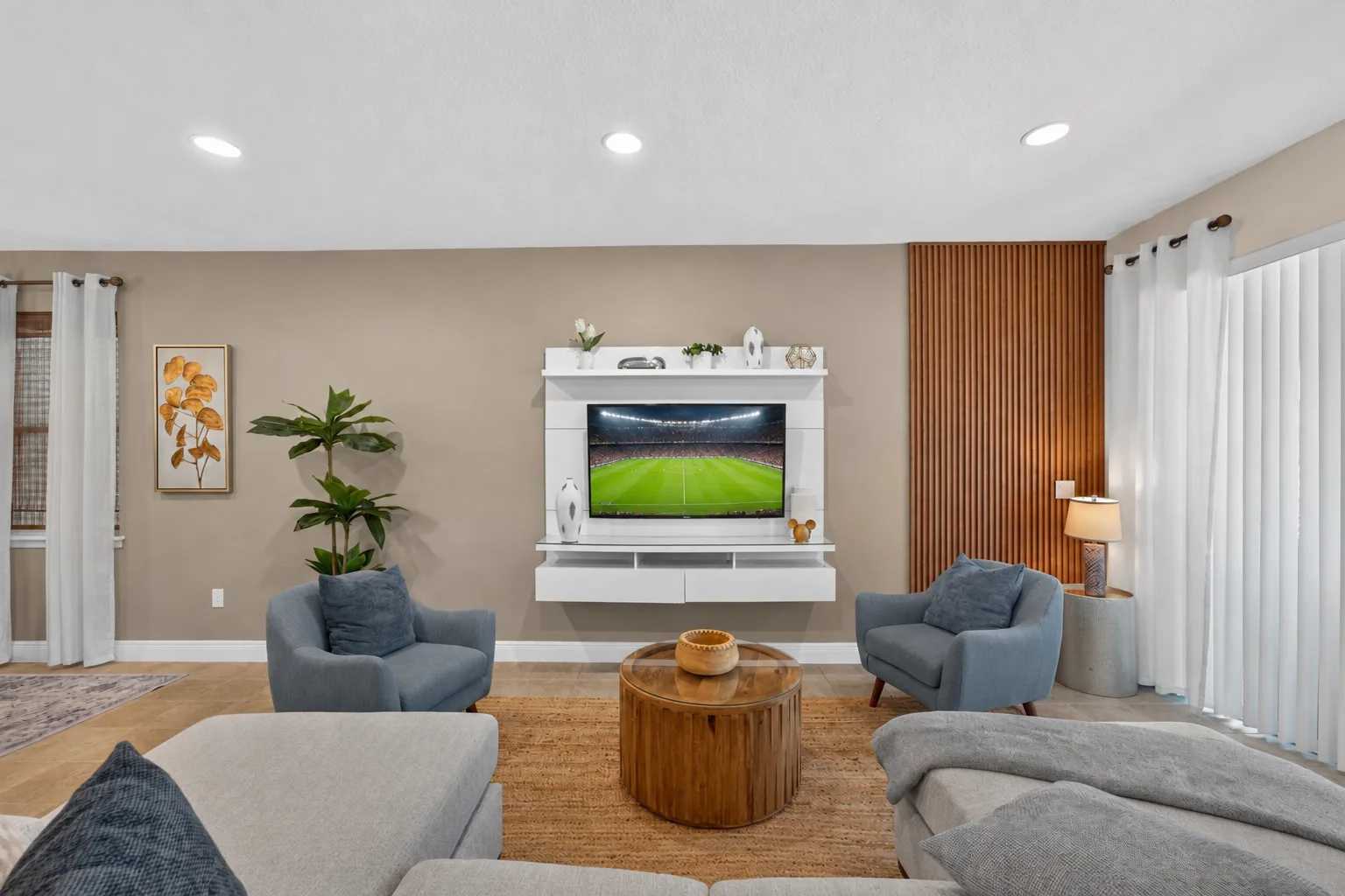 A living room with seating arranged around a television and wooden coffee table.