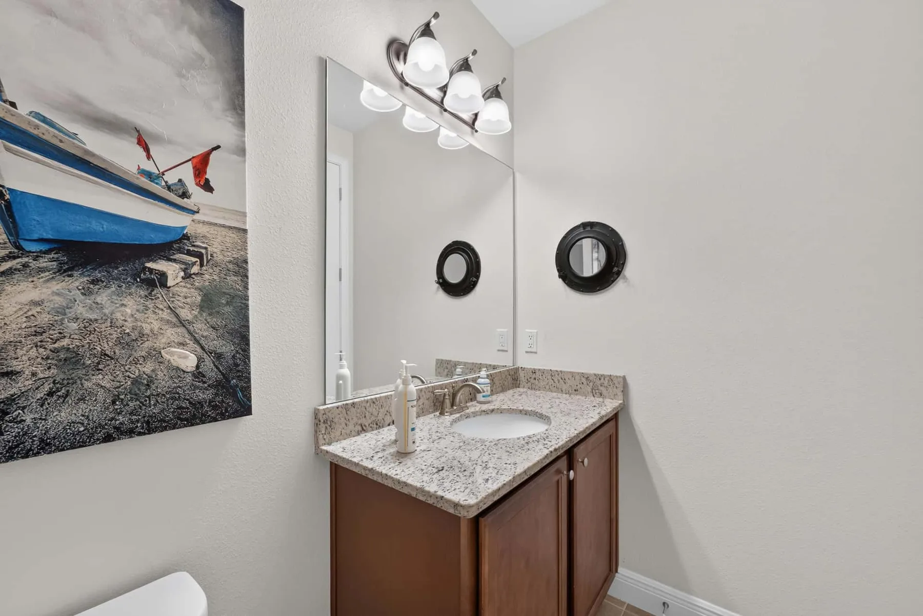 A bathroom vanity with a sink and mirror beneath a row of lights.