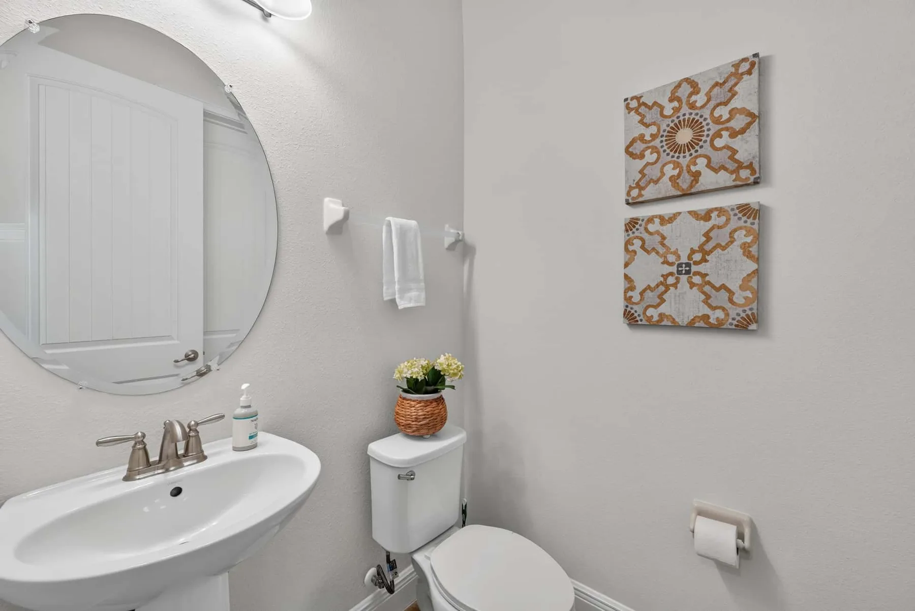 A bathroom with a sink, toilet, and two decorative wall panels.