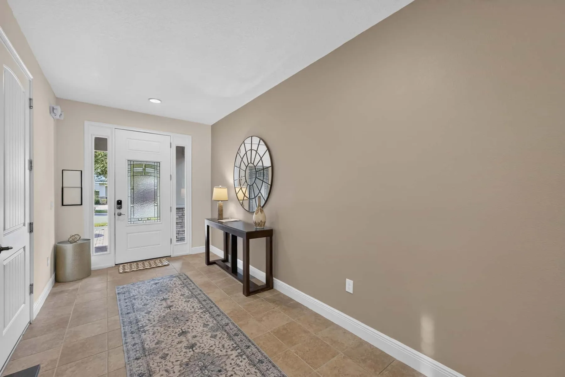 An entryway with a glass-paneled front door, a narrow table, and a runner rug.