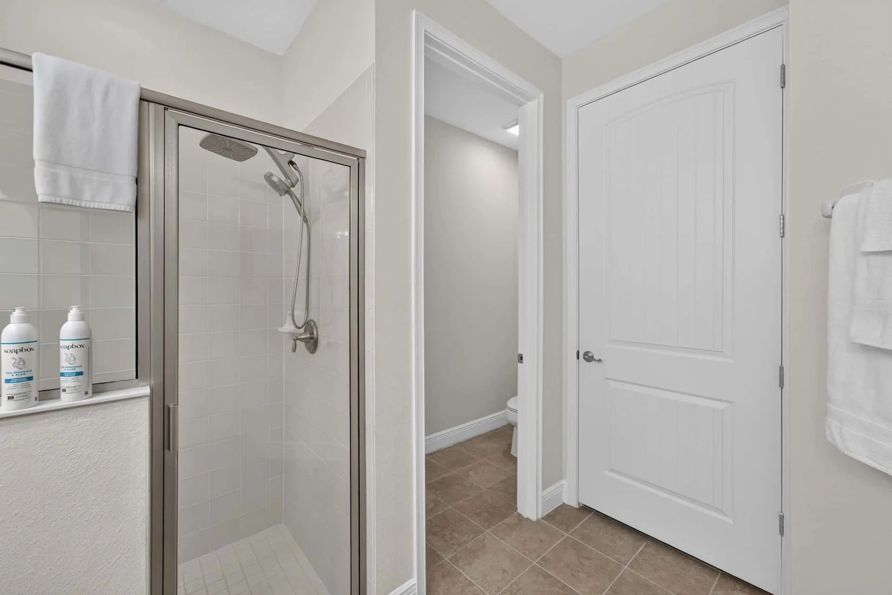 A bathroom with a glass shower and a white door.