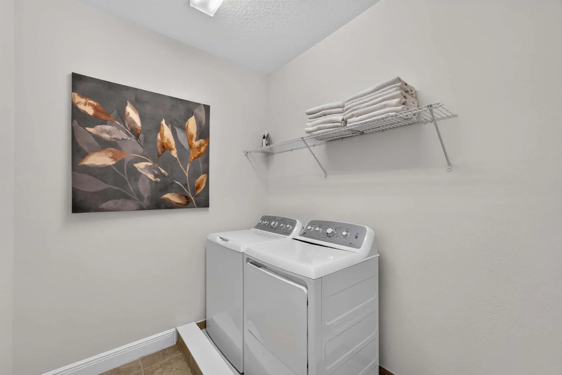 A laundry area with a washer and dryer beneath a shelf of folded towels.