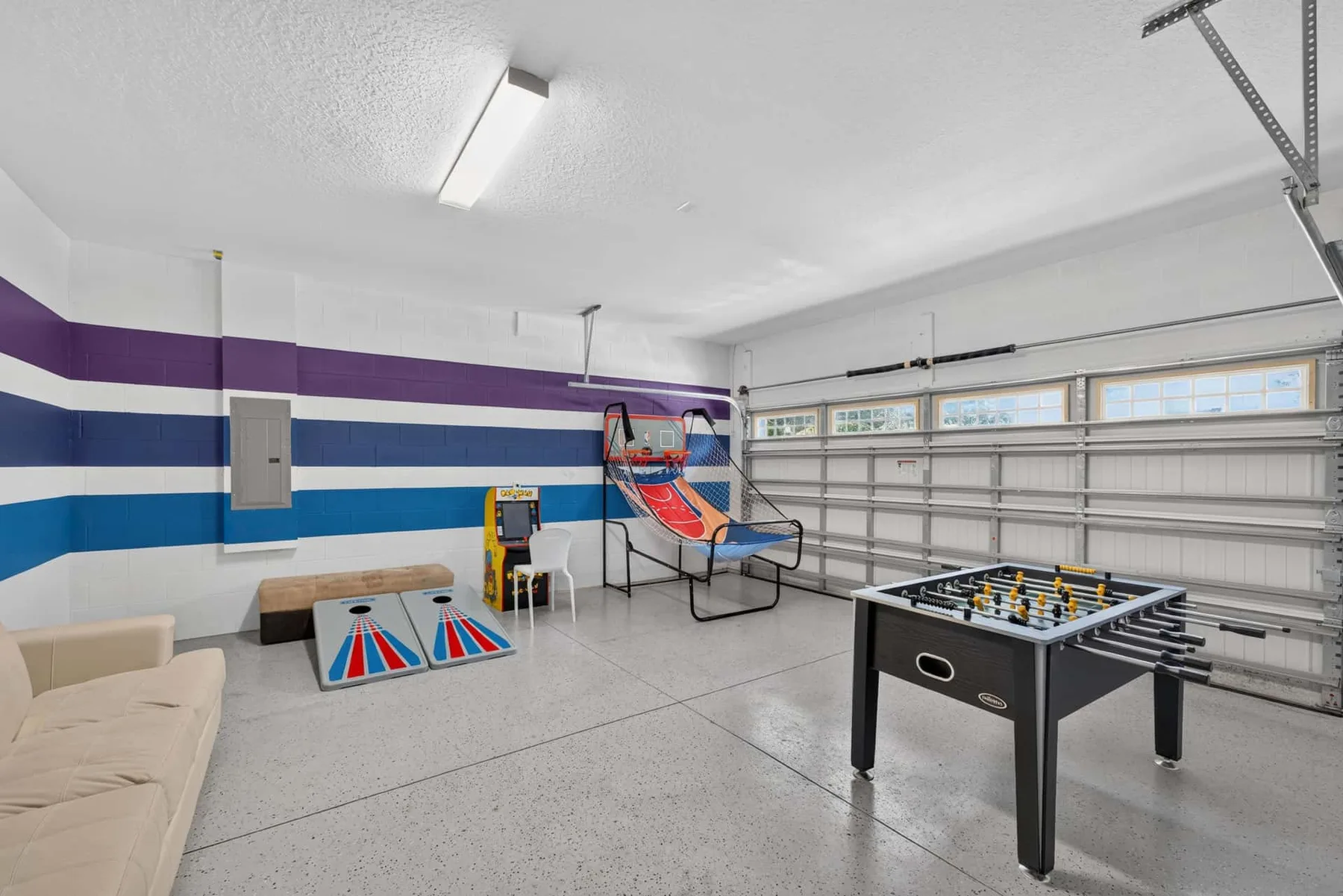 A garage game room with a foosball table and arcade-style seating.