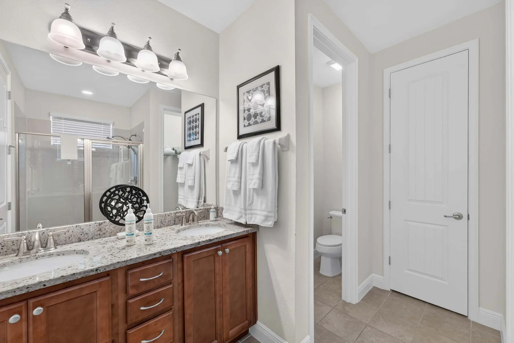 A bathroom vanity with a wide mirror, countertop, and towels hanging nearby.