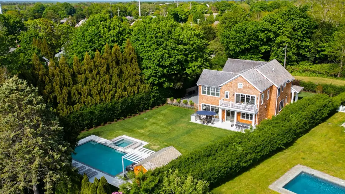 Aerial view of a brick house with a green lawn and swimming pools.