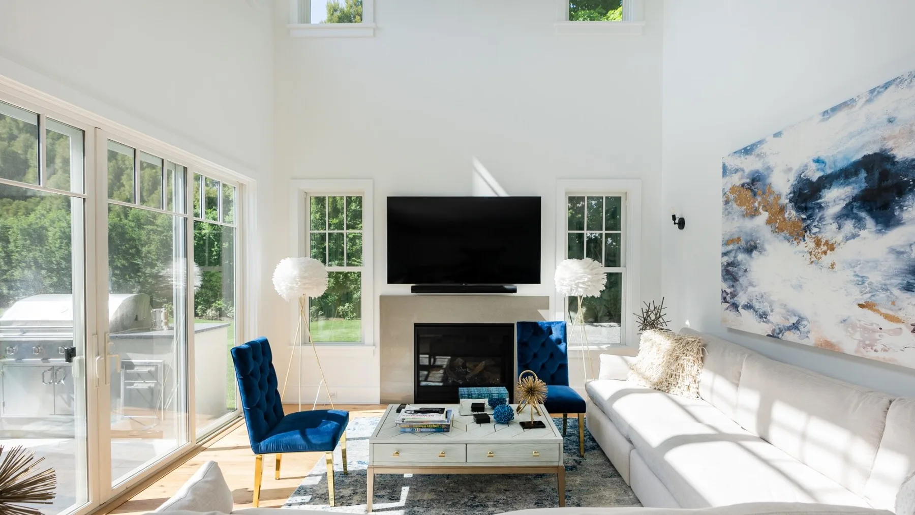A bright living room with a television, seating, and large windows.