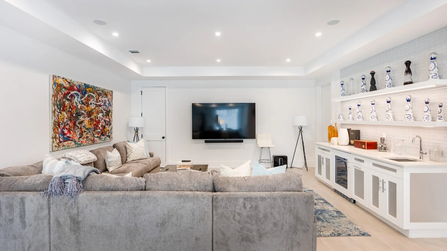 A bright living room with a large sectional facing a wall-mounted television.