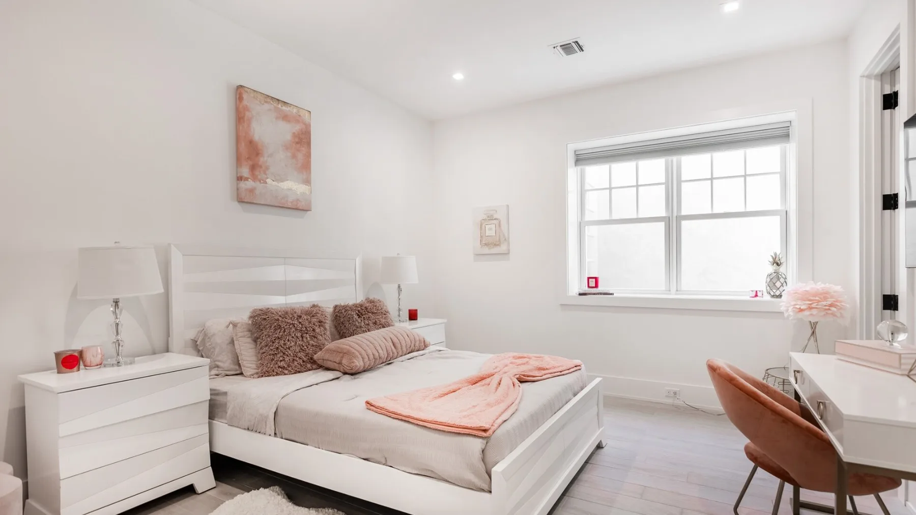 A bright bedroom with a neatly made bed and a large window.