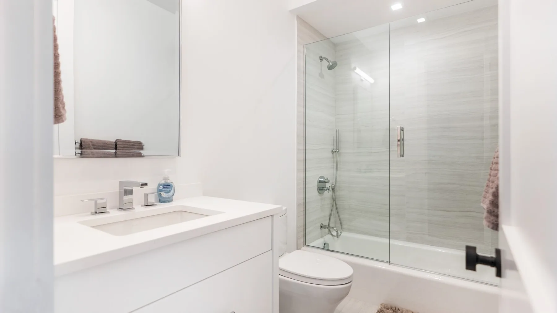 A bright bathroom with a white vanity and a glass-enclosed shower.