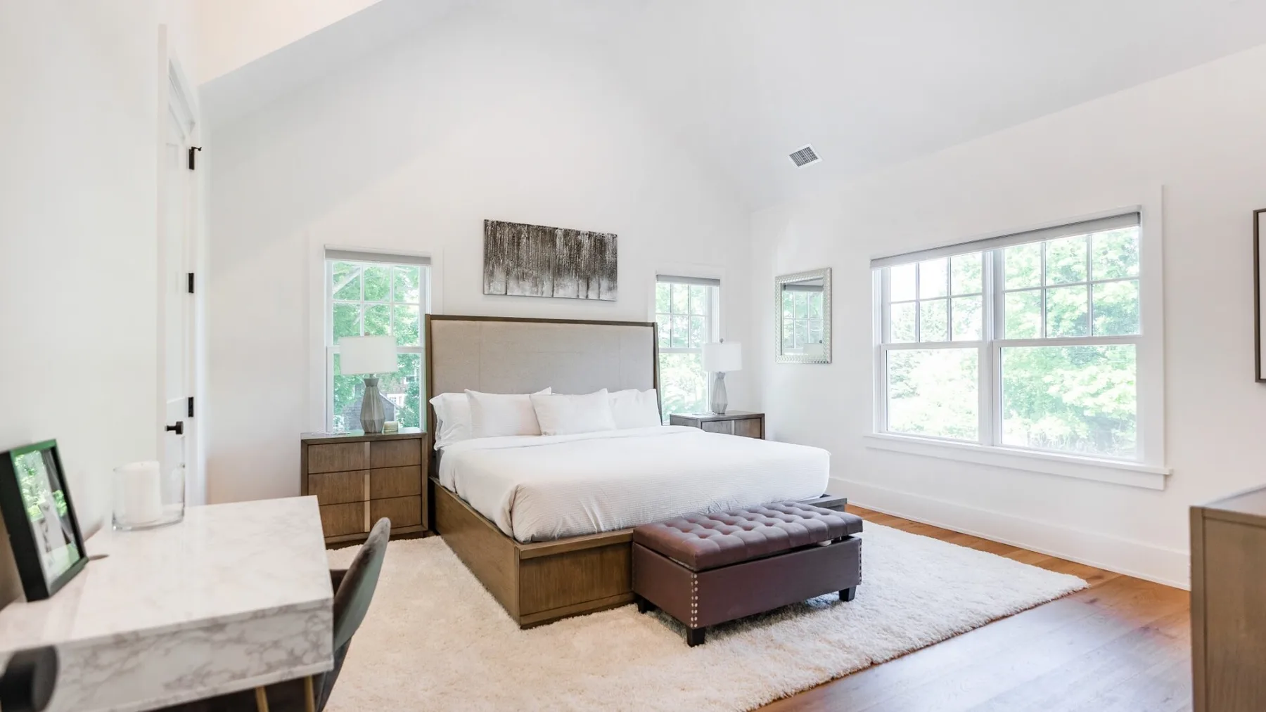 A bright bedroom with a bed and large windows.