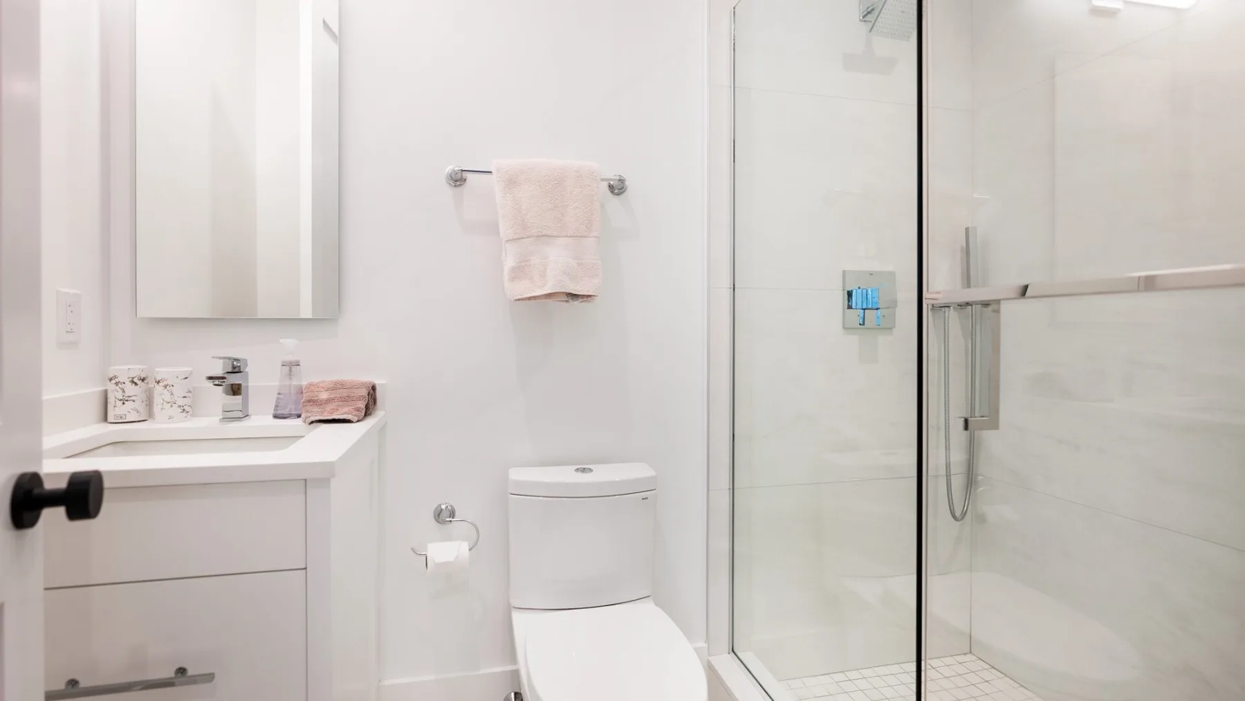 A bright bathroom with a vanity, toilet, and glass shower.