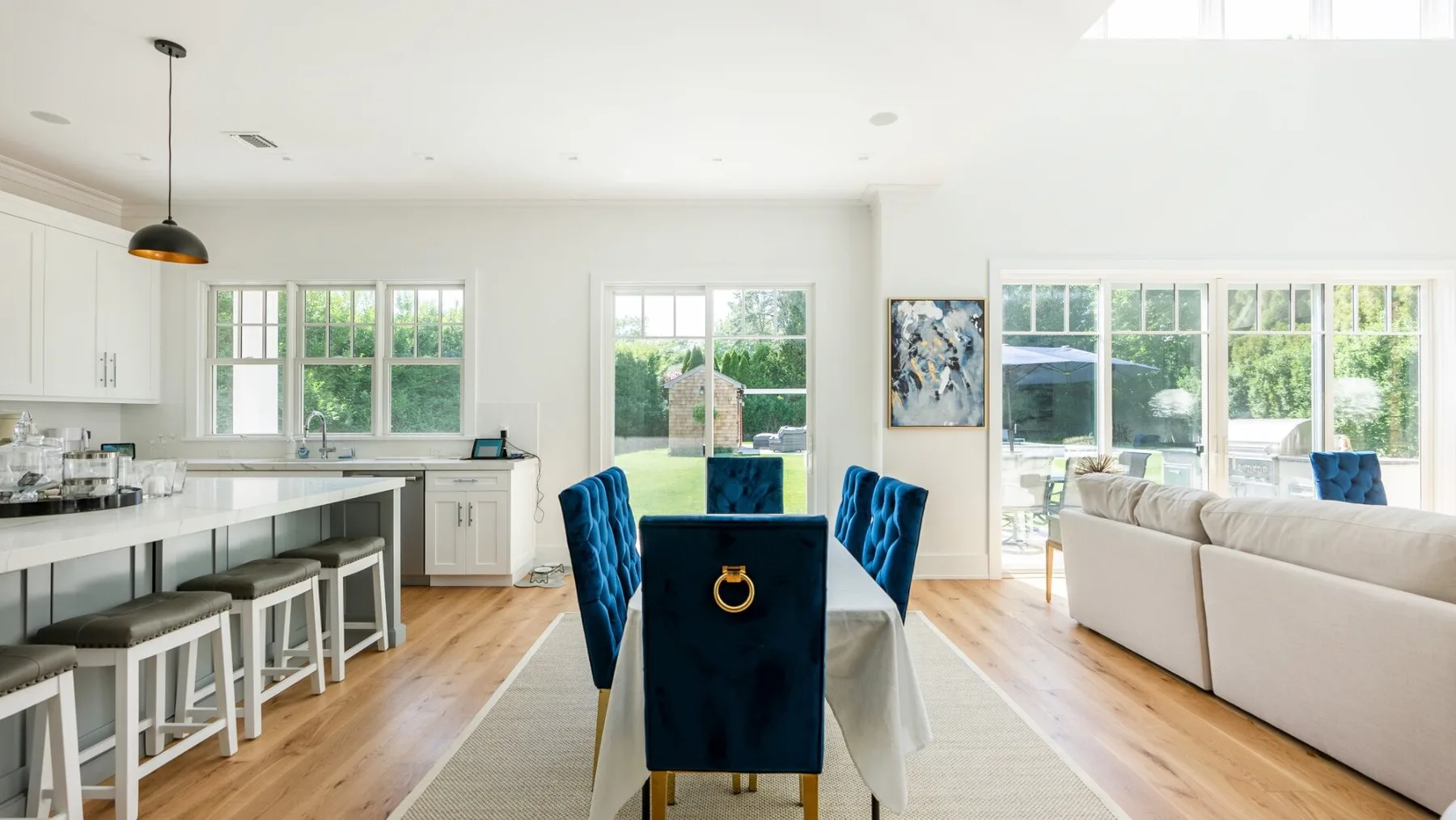 A bright open-plan kitchen and dining area opens onto a living room with large windows.