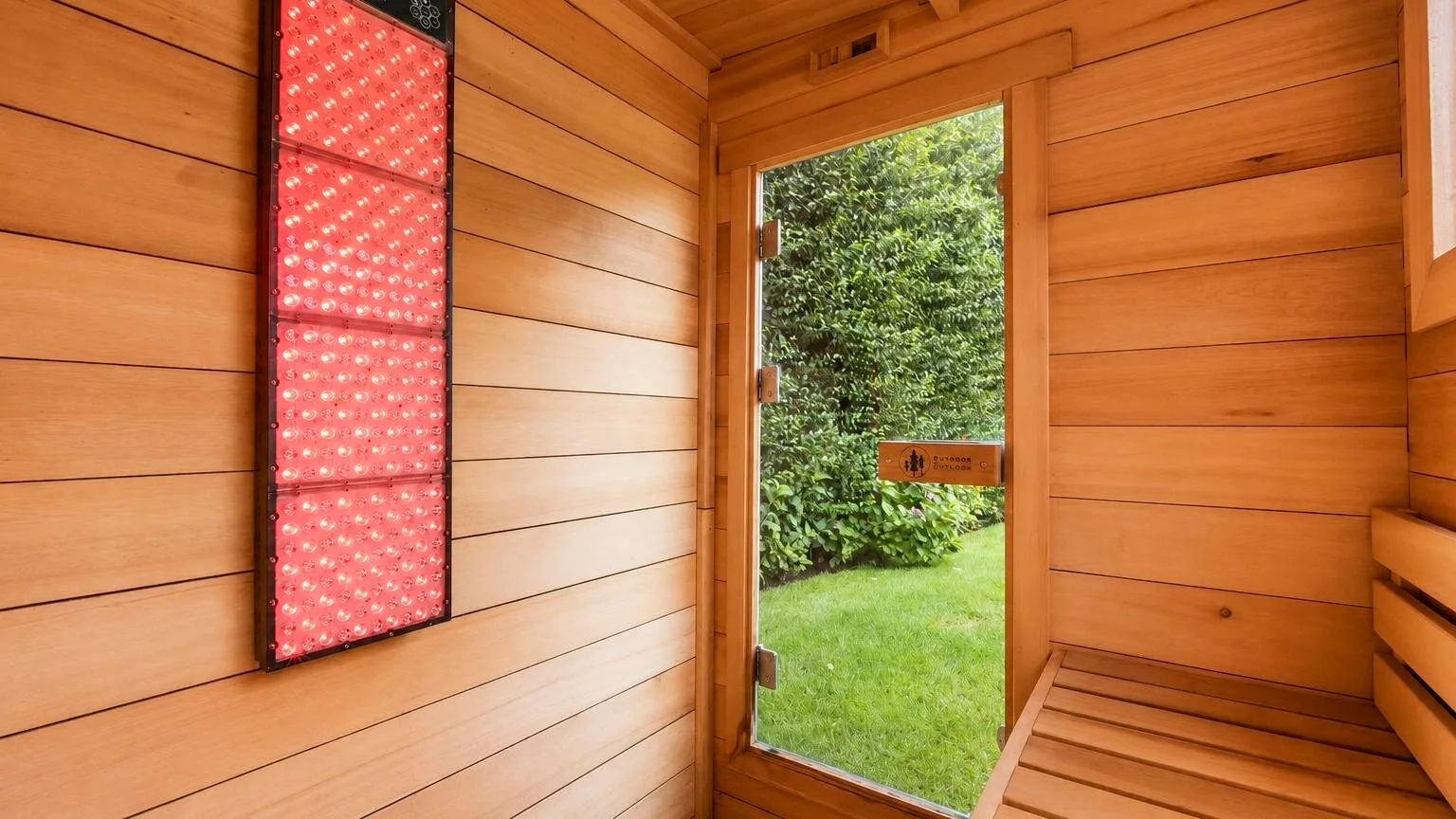 A wood-paneled room has a bench and an open doorway facing greenery.