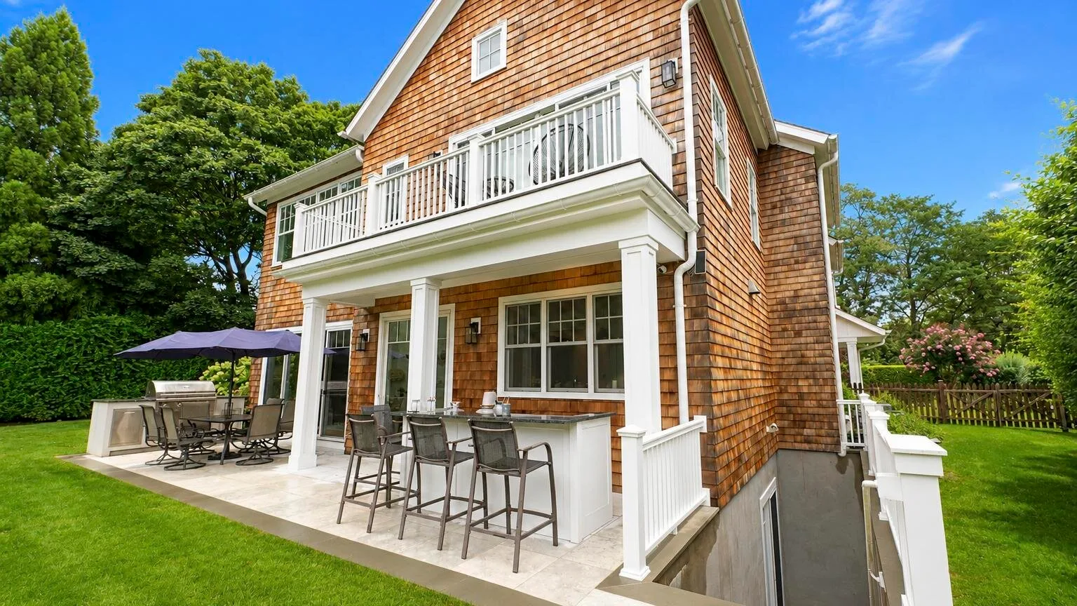 A brick house with a covered patio and an upper balcony.