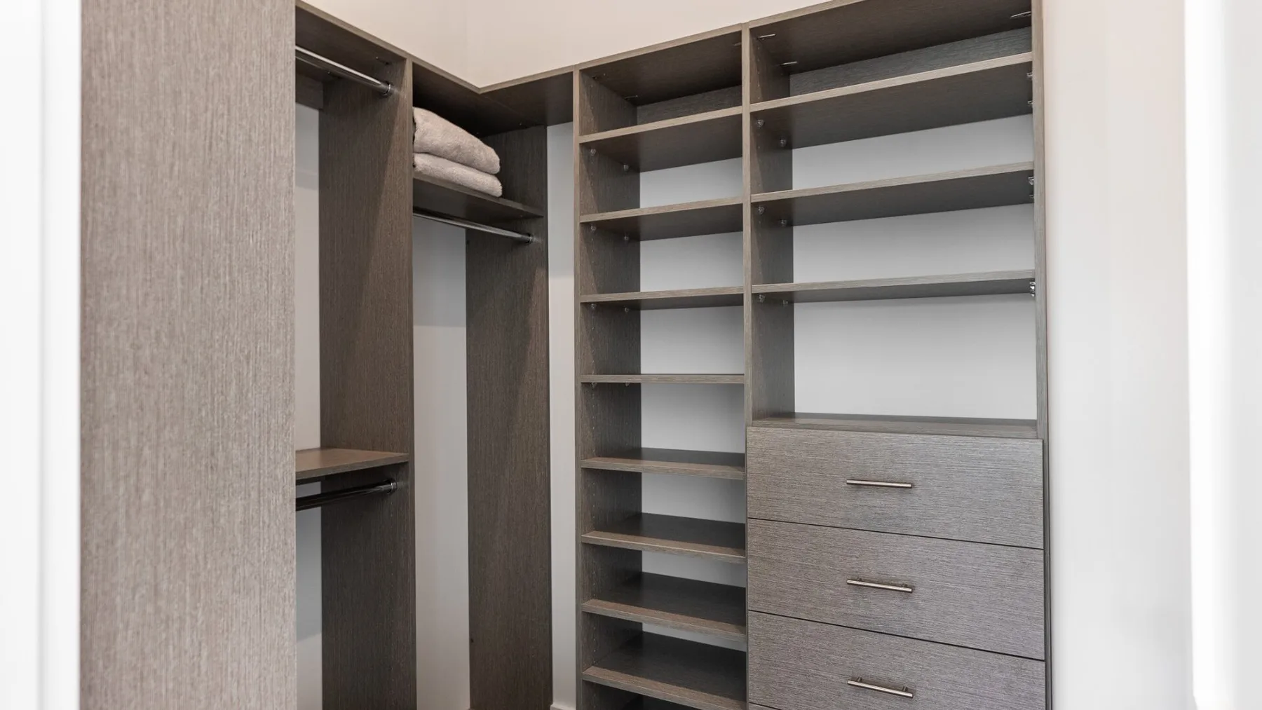 A walk-in closet with open shelving, drawers, and folded towels.