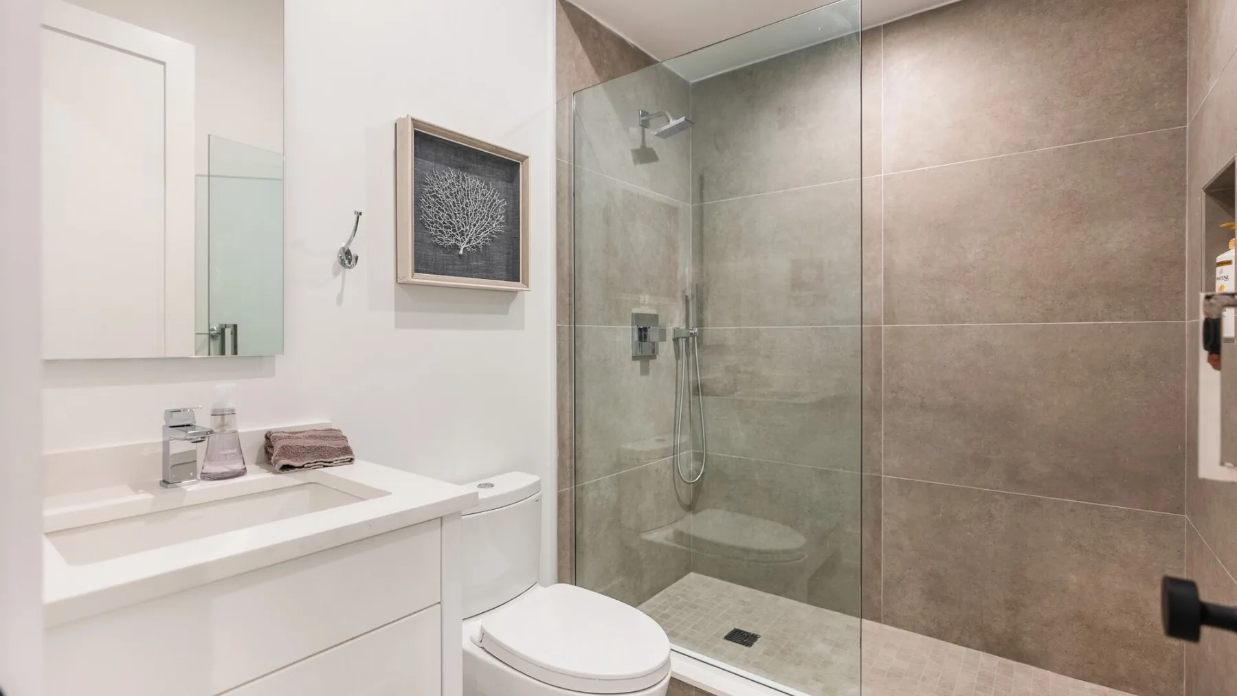 A modern bathroom with a glass-enclosed shower and white vanity.