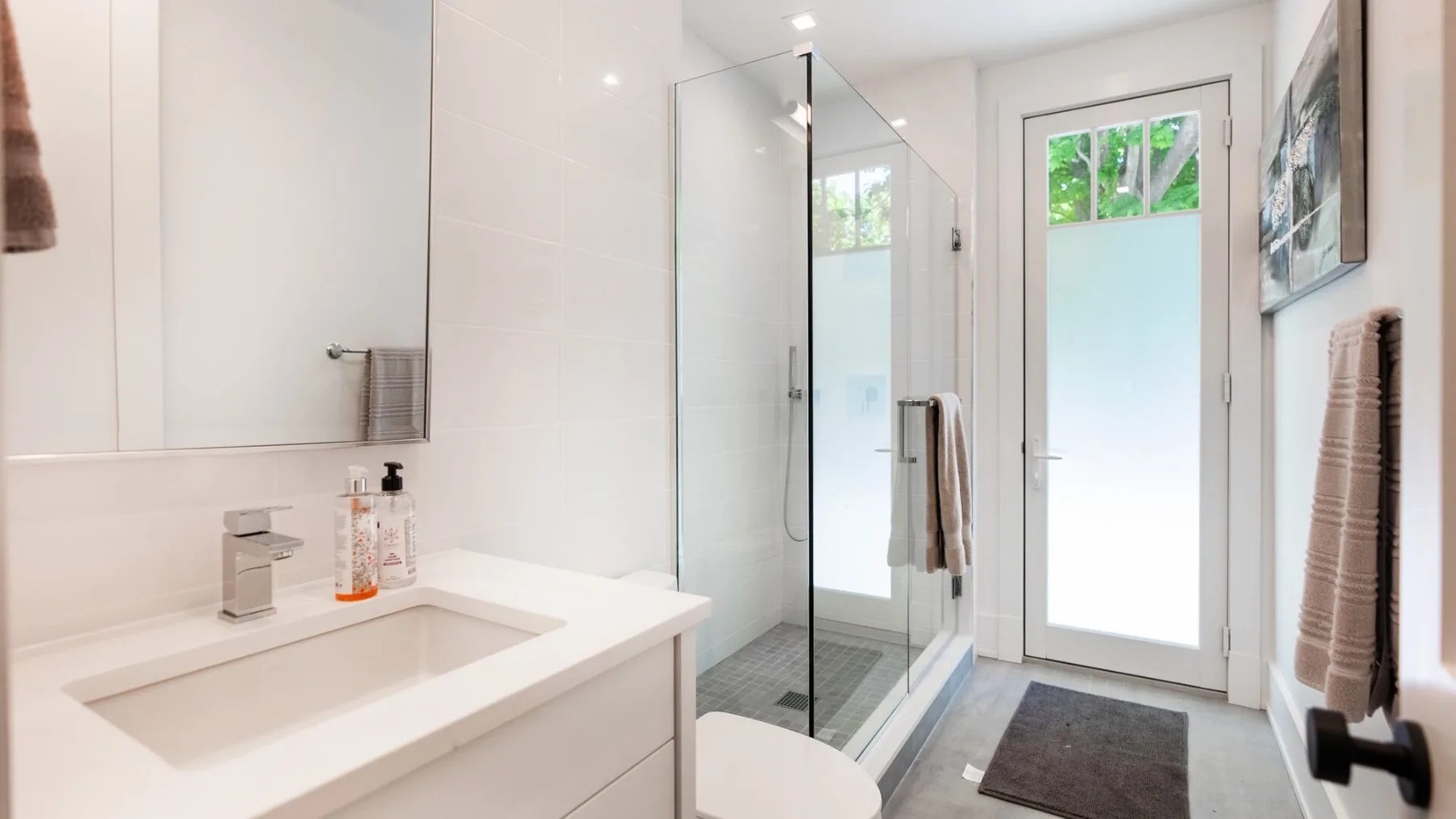 A bright bathroom with a sink, shower, and glass-paned door.