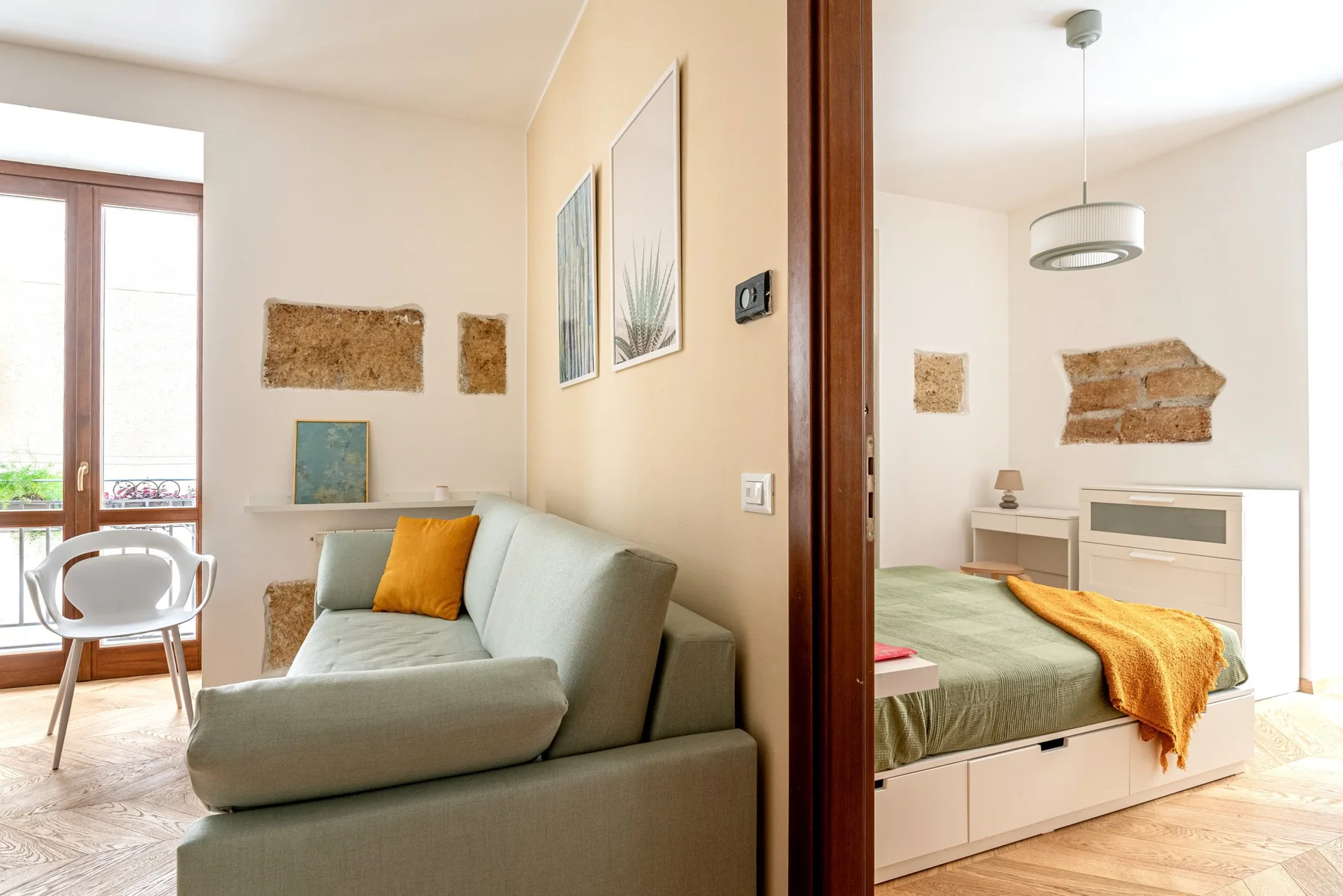 A sitting area with a sofa beside a bedroom with a bed.
