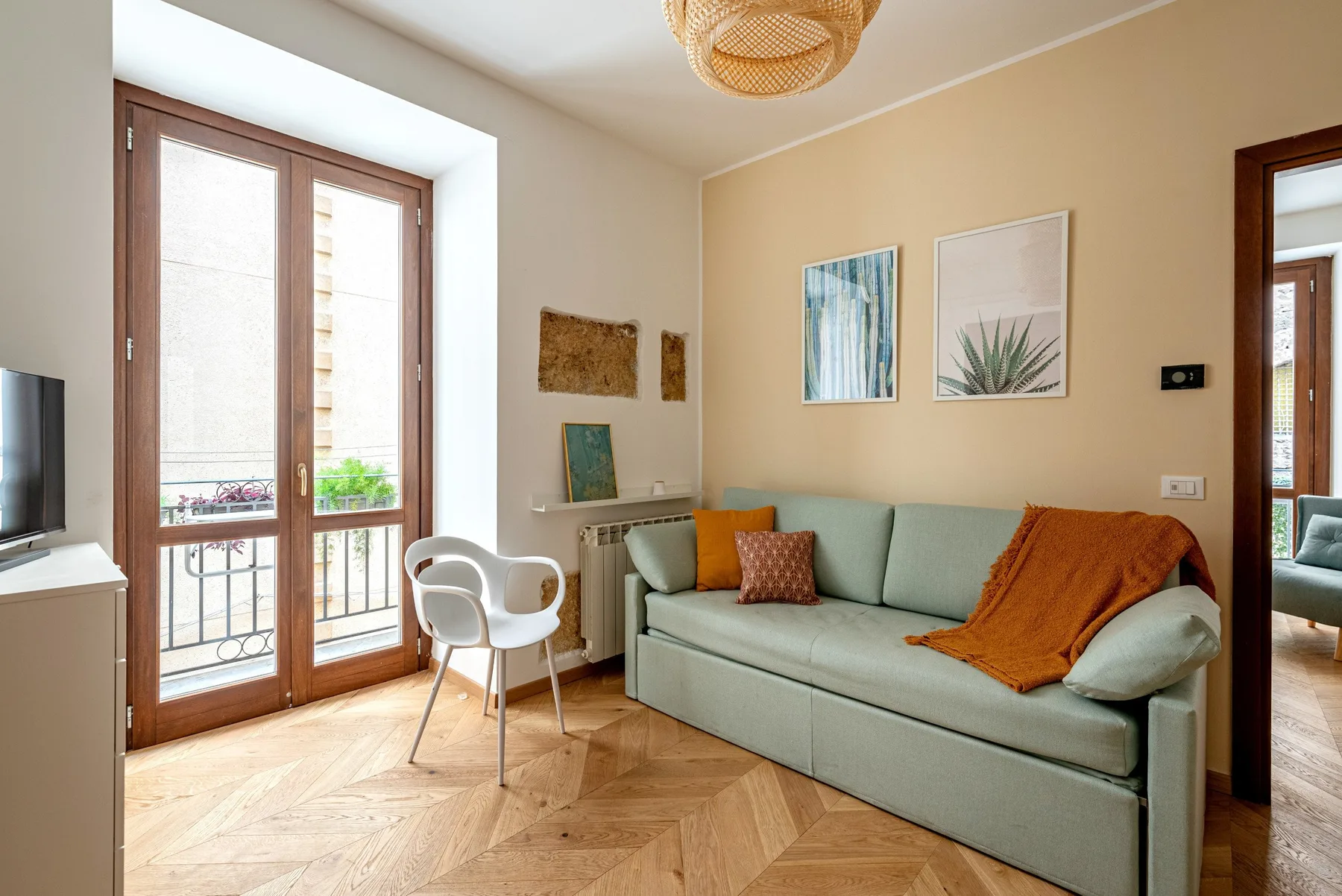 A living room with a pale green sofa and tall glass doors.