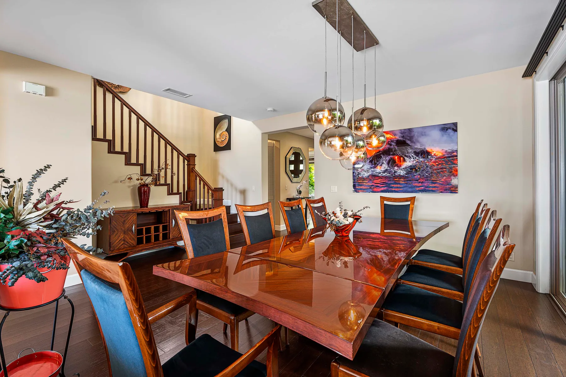 A dining room with a long wooden table, chairs, and colorful wall art.