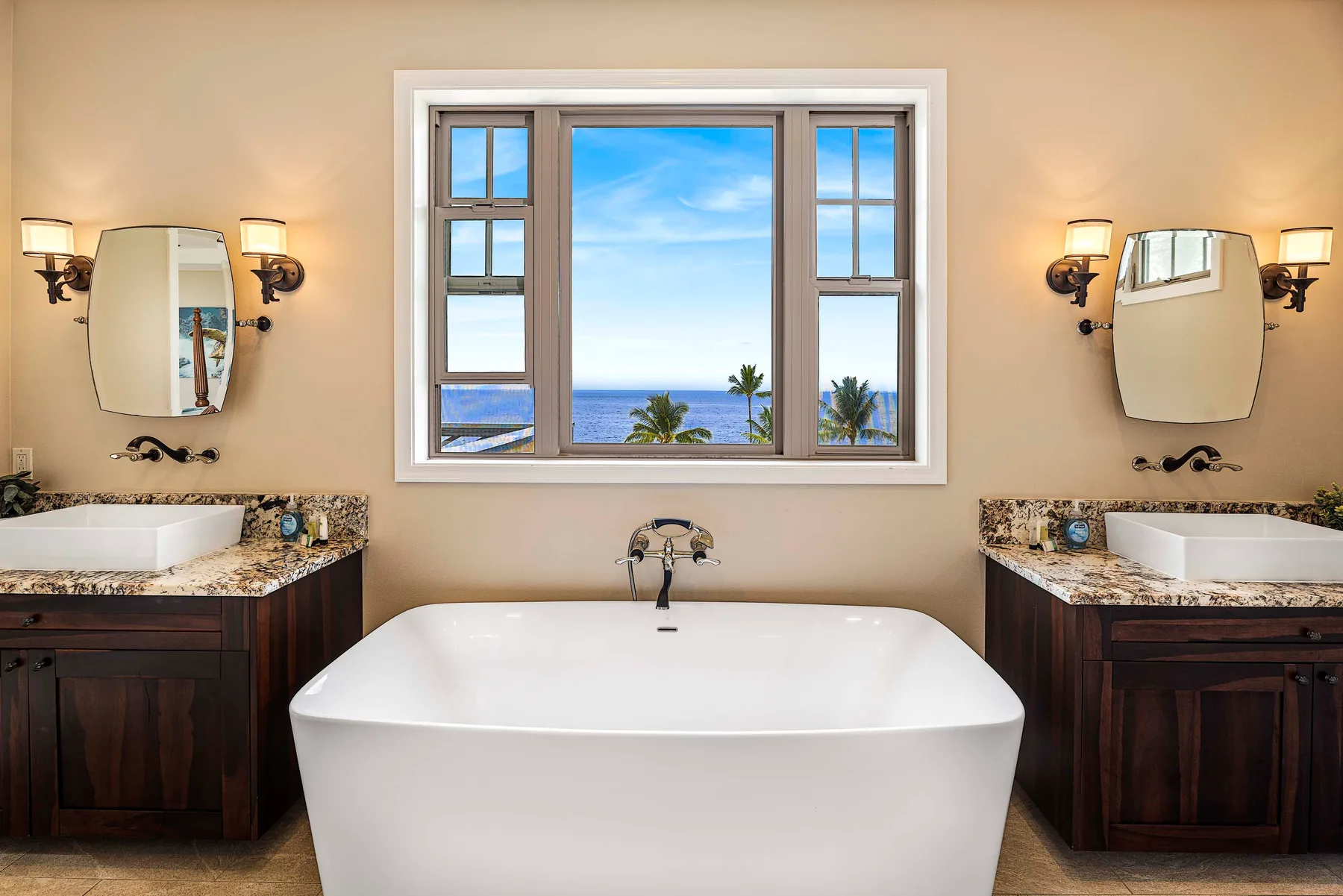 A bathroom with a freestanding bathtub beneath a window overlooking the ocean.
