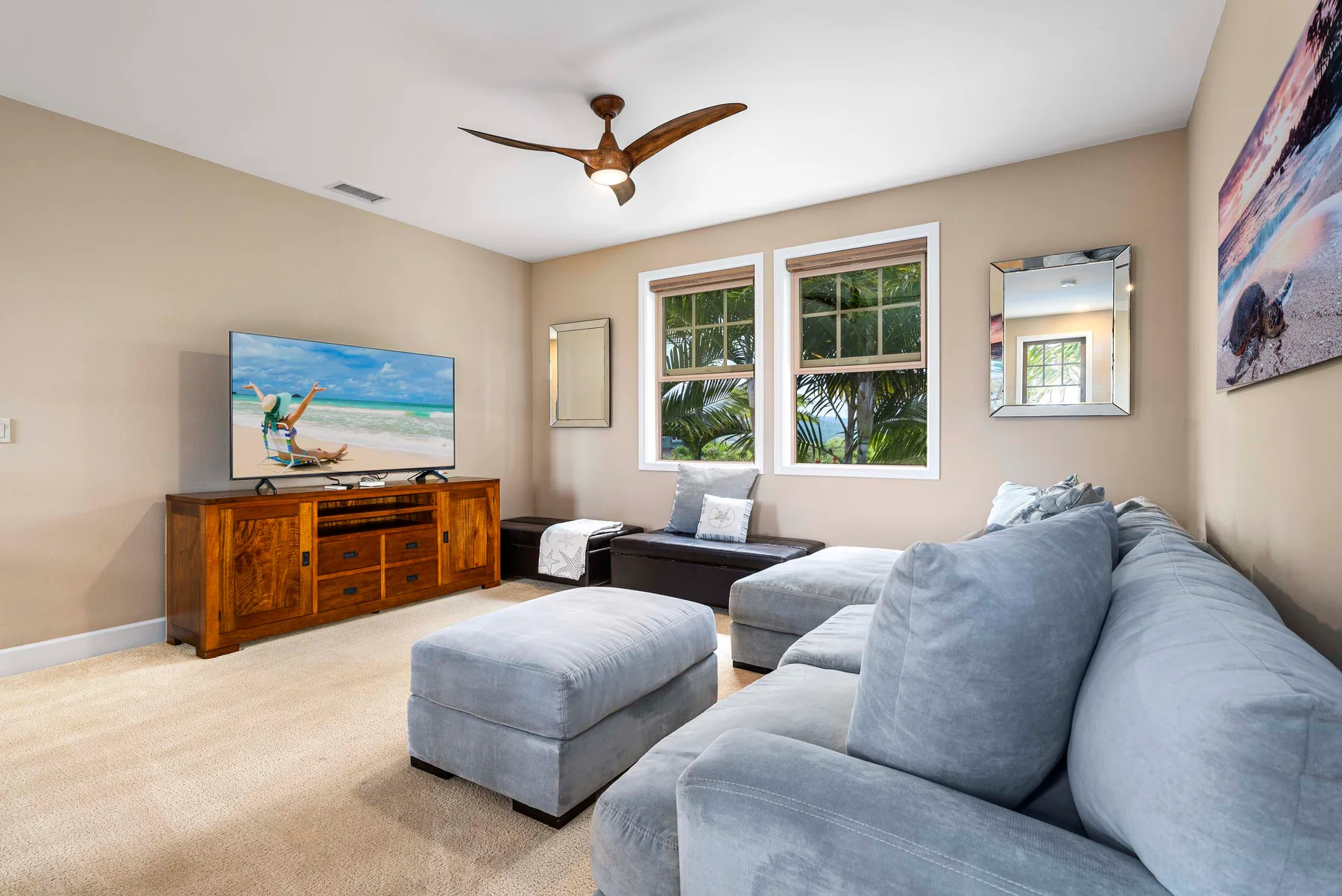A living room with a sectional seating area, ottoman, and television.