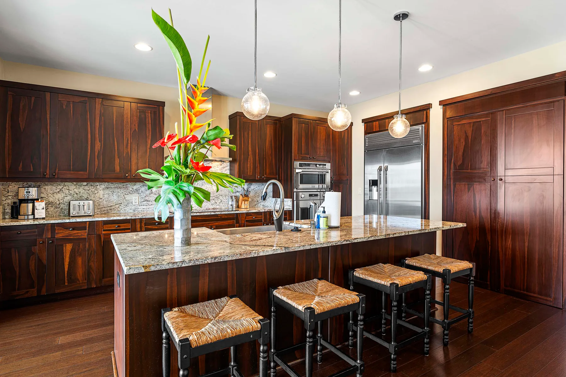 A kitchen with dark wood cabinets, a stone island, and seating.