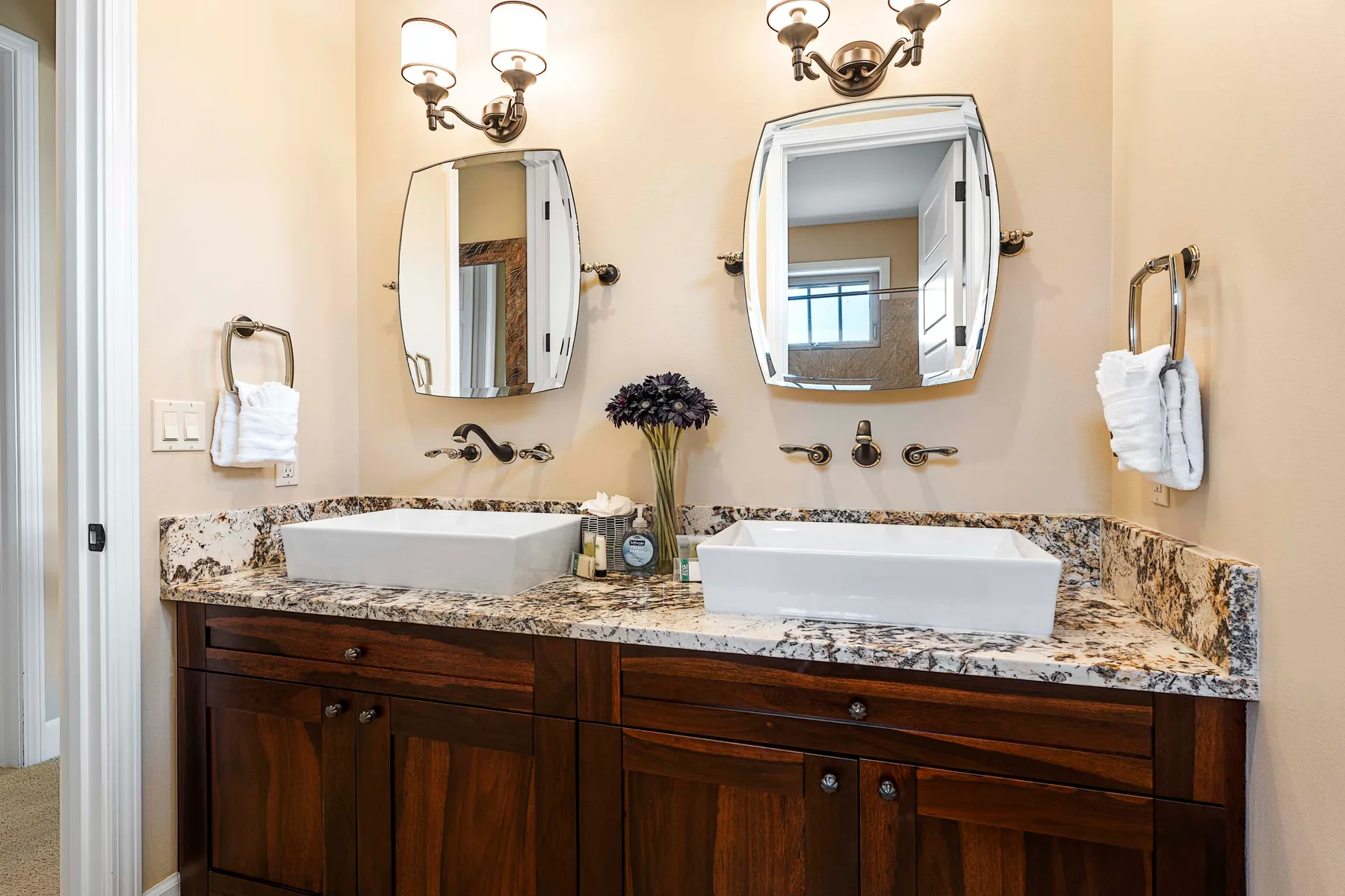A bathroom vanity with two sinks, mirrors, and wall lights.