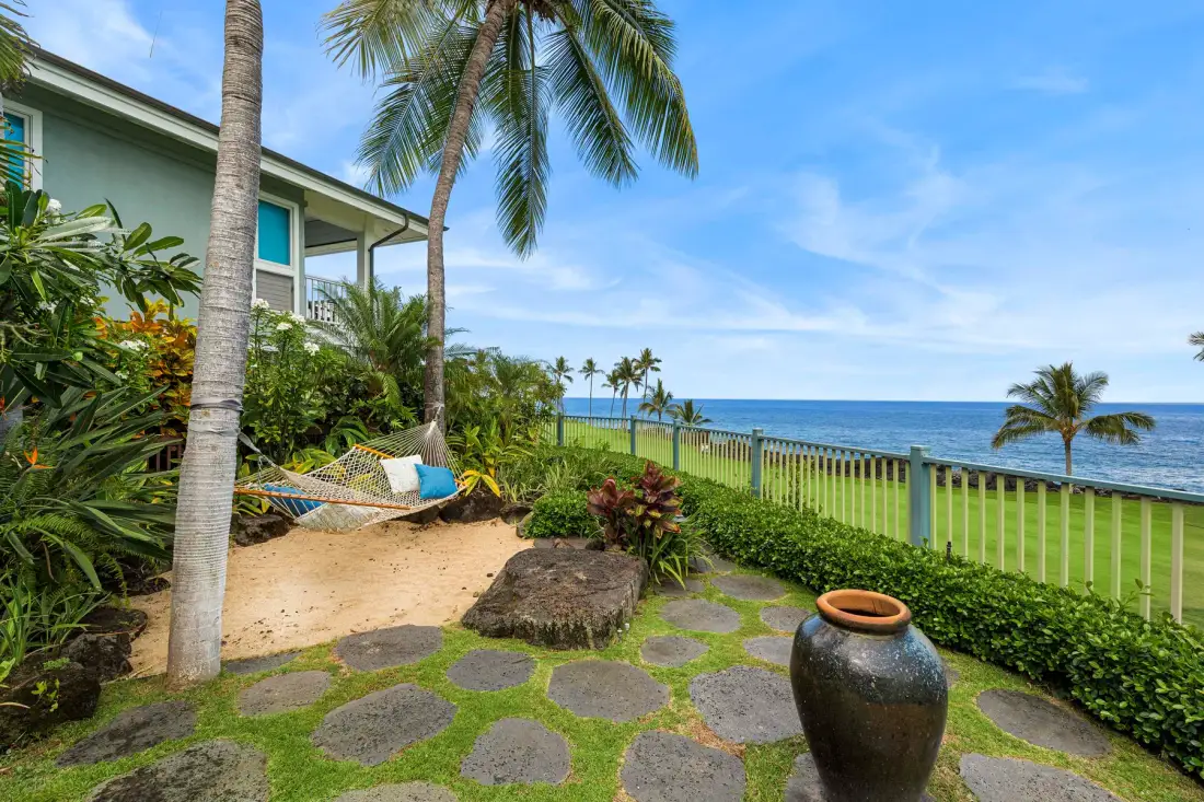 A tropical seaside garden with stepping stones, palms, and an ocean view.