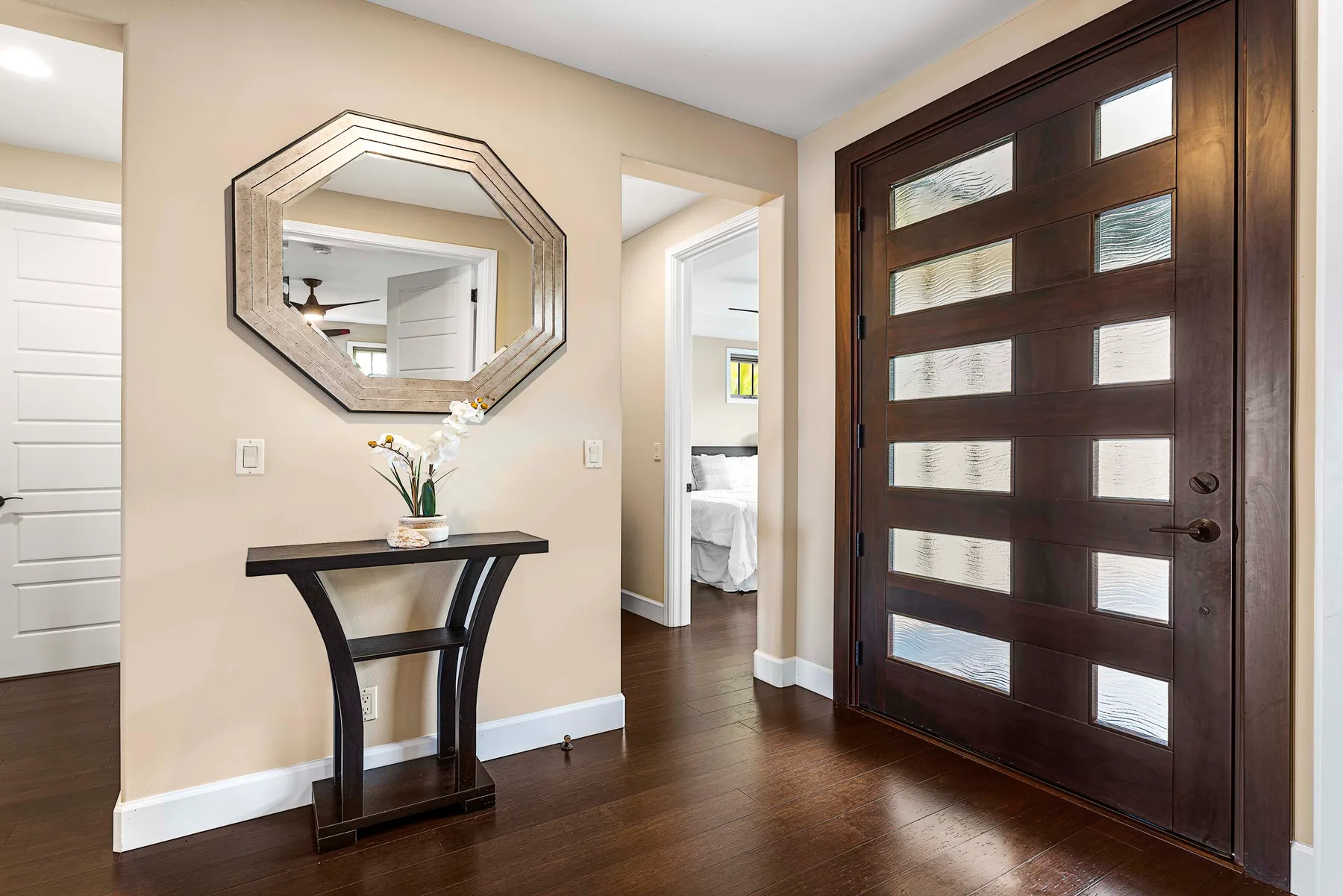 An entryway with a dark front door, a console table, and a geometric mirror.
