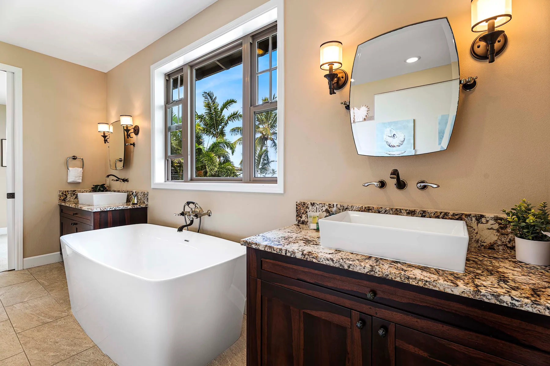 A bathroom with a freestanding tub and a vanity beneath a large mirror.