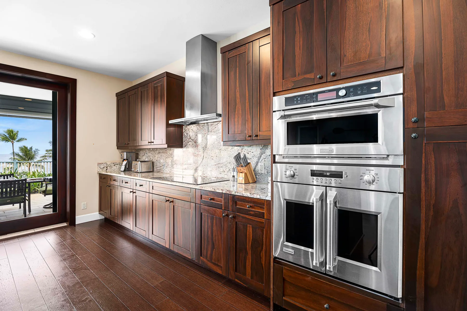 A kitchen with dark wood cabinets, a stone countertop, and stainless steel appliances.
