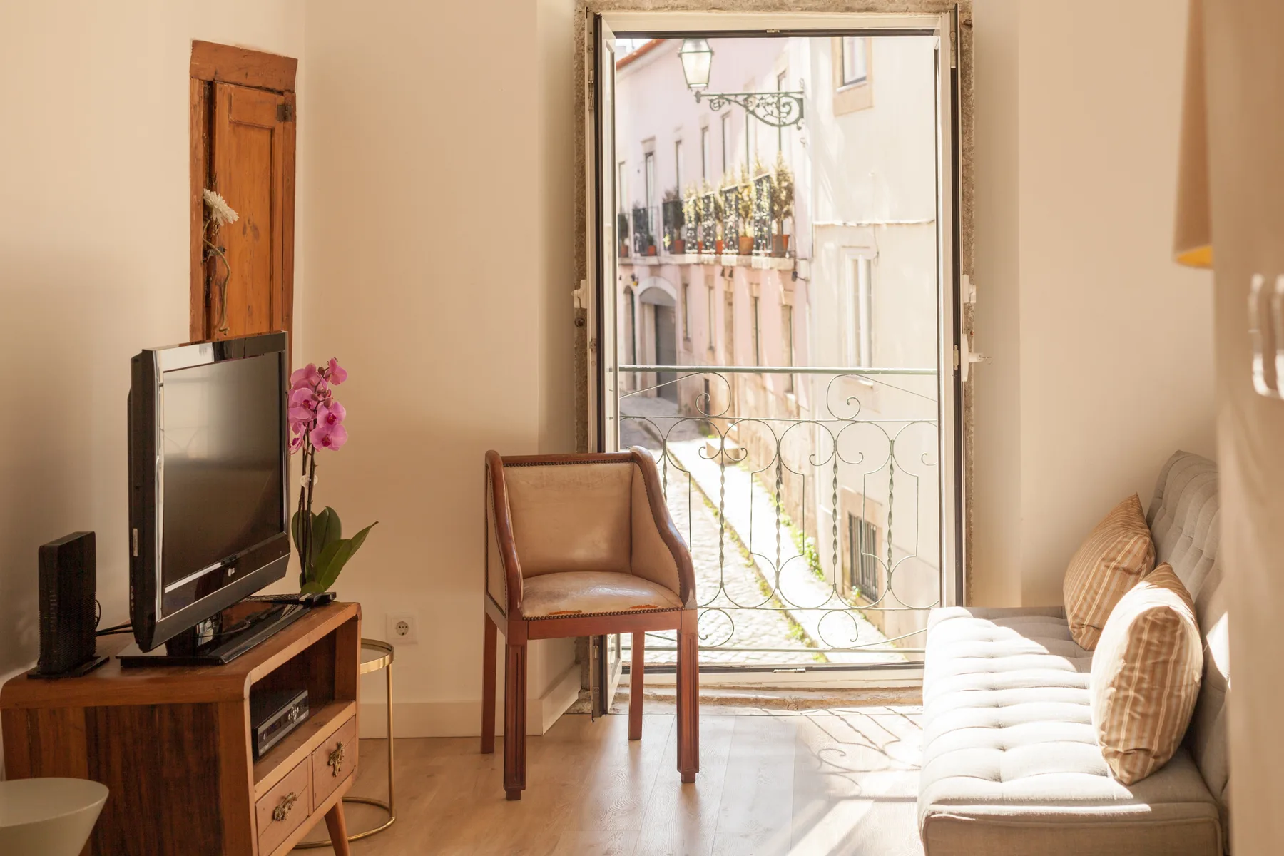 Una sala de estar con asientos y un televisor junto a una ventana luminosa.