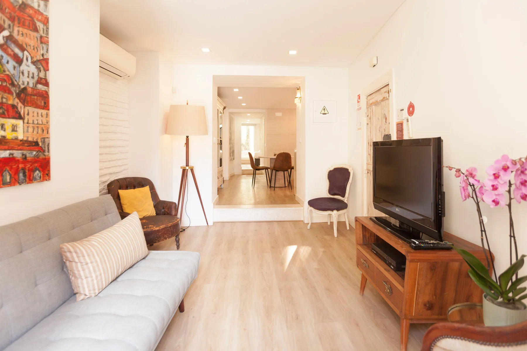 Una sala de estar luminosa con asientos, un televisor y vista al comedor.
