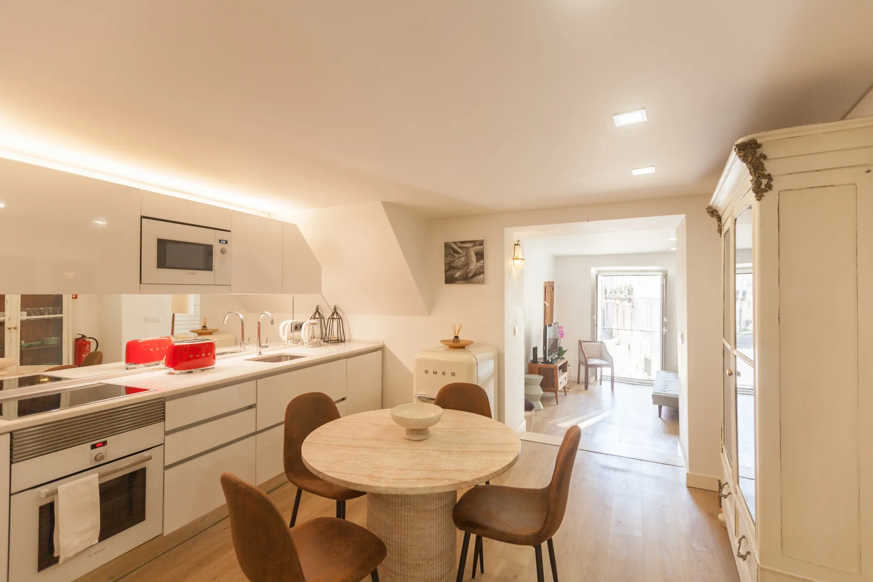 Una cocina luminosa con comedor se abre hacia una sala de estar.