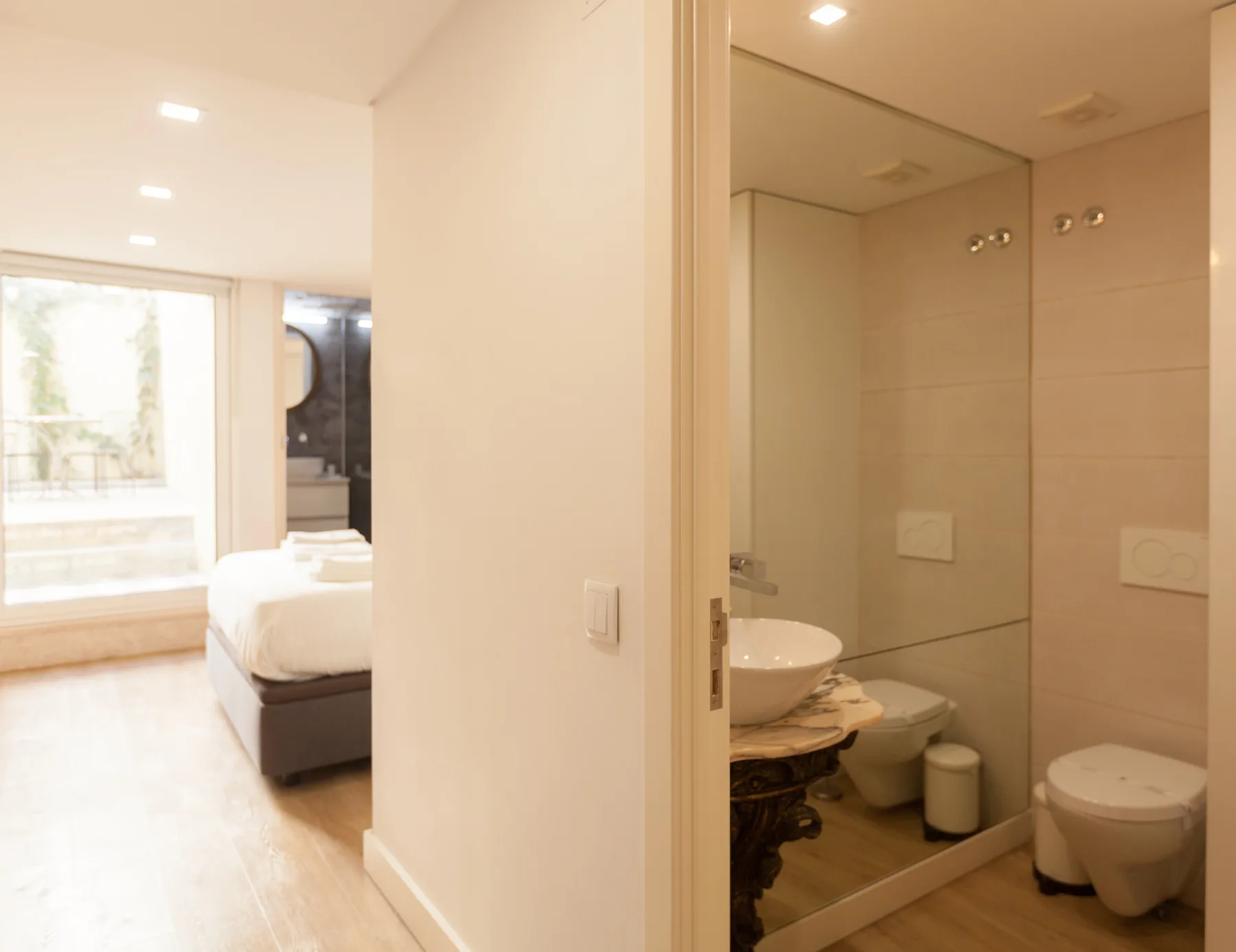 Un dormitorio luminoso junto a un baño con una mampara de ducha de vidrio.