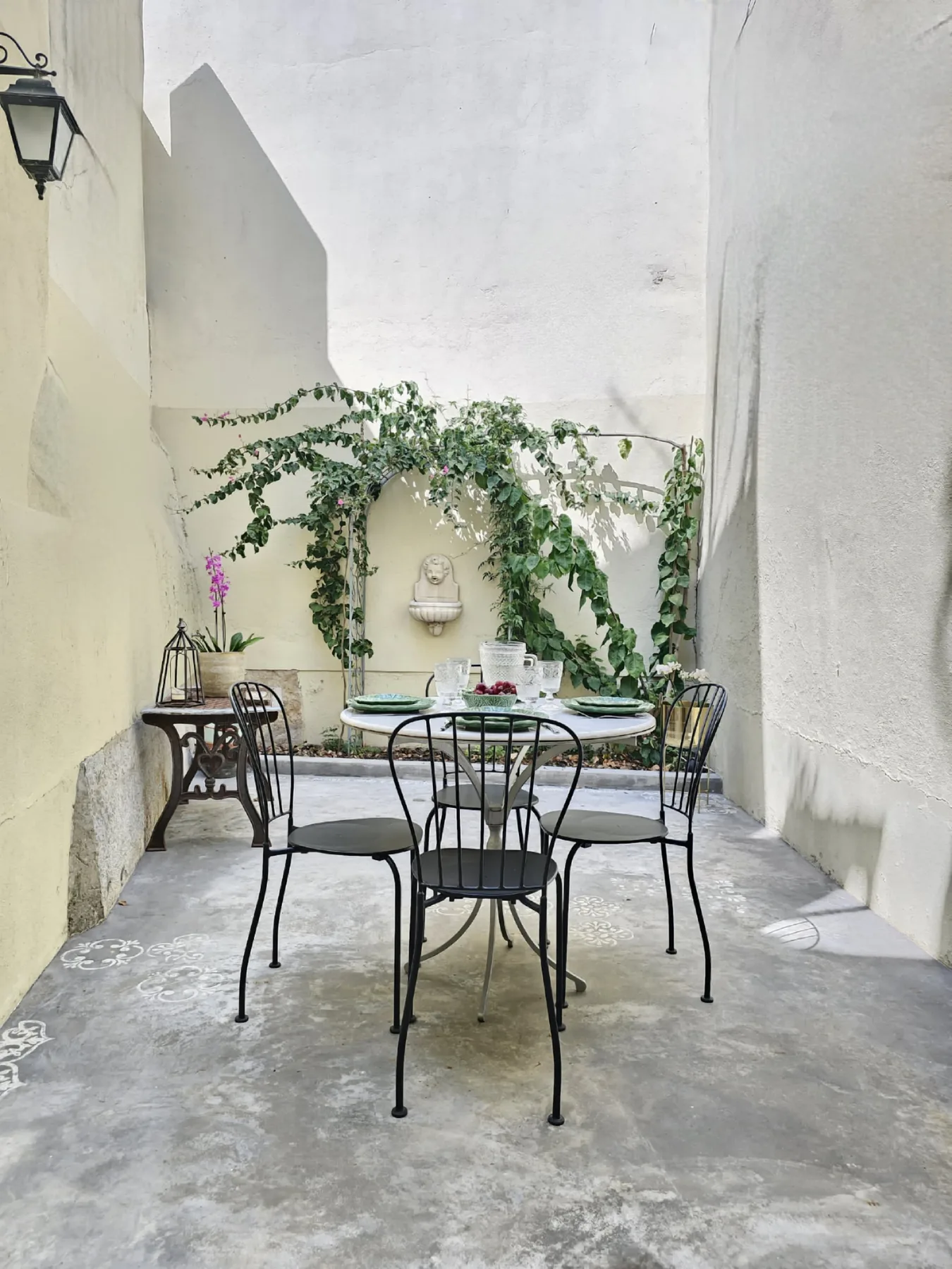 Un comedor en un patio con una mesa y asientos bajo enredaderas.