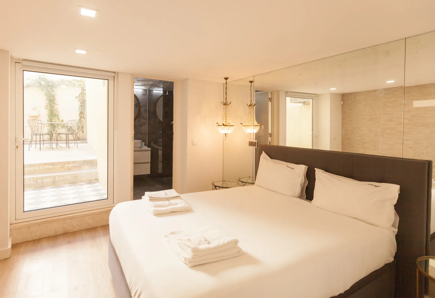 Un dormitorio con una cama grande y una puerta de vidrio que da a una terraza.