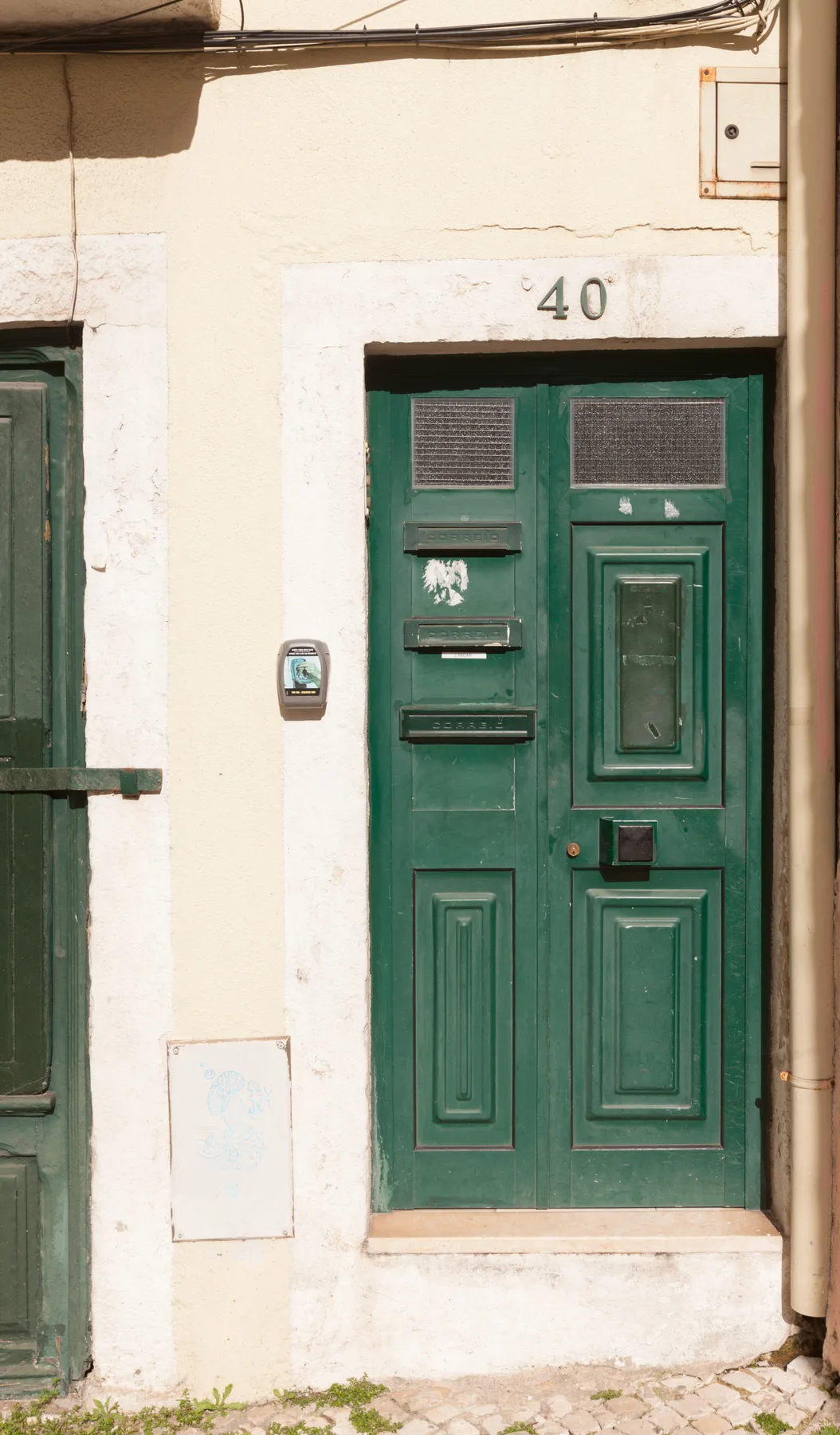 Una puerta de entrada verde con paneles en una pared exterior clara.
