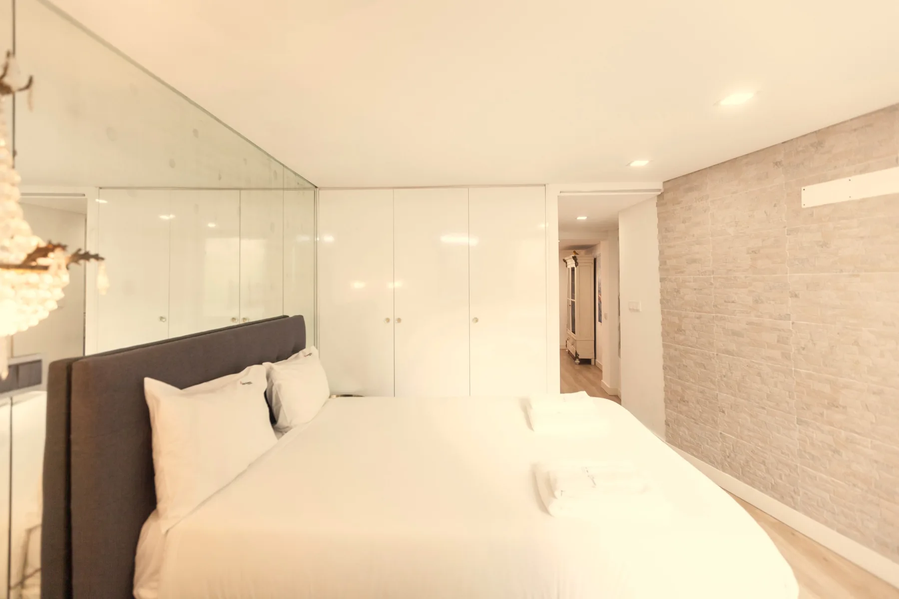 Un dormitorio luminoso con una cama grande y una mampara de vidrio.