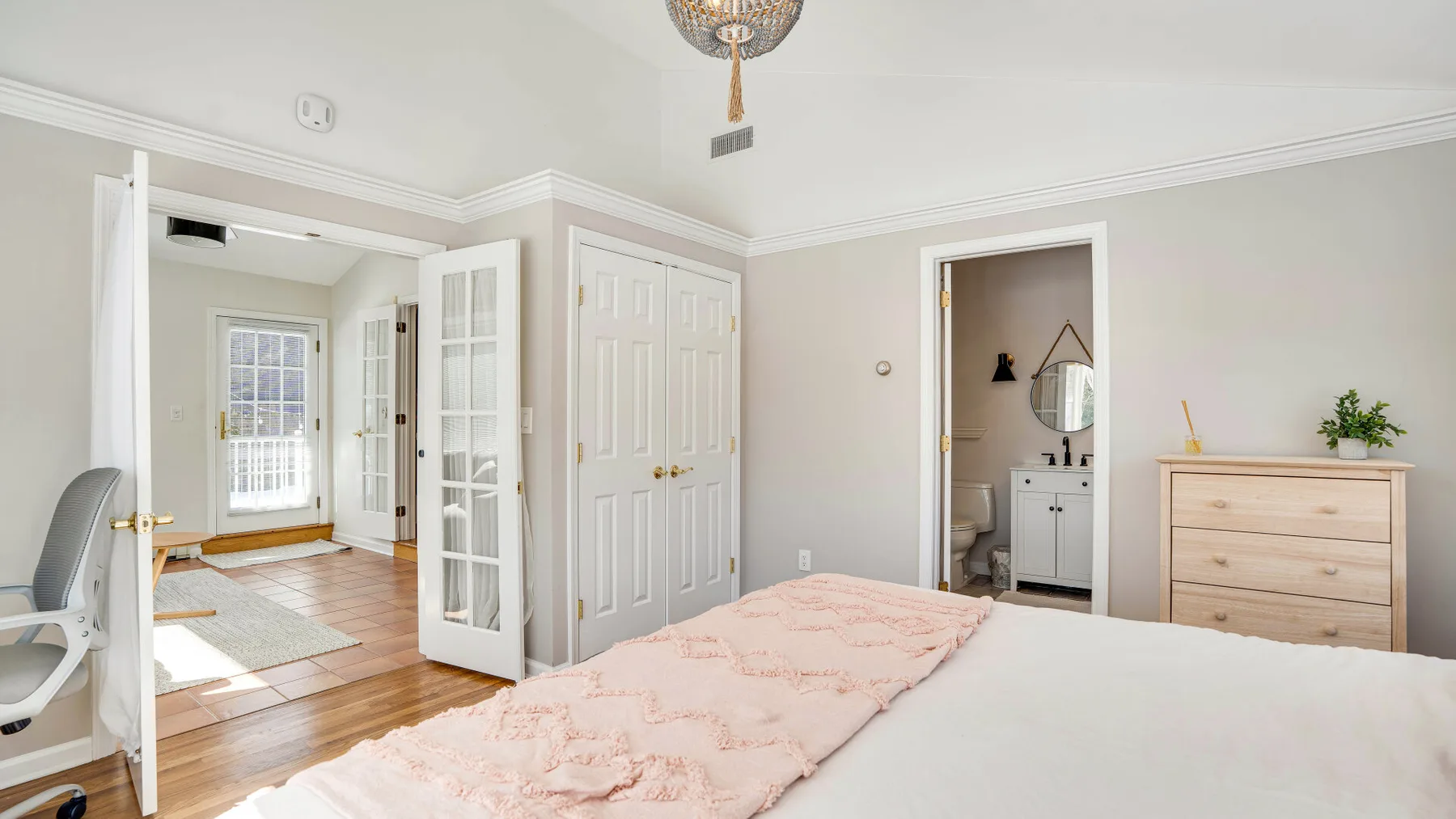 Un dormitorio con una cama, una cómoda y una puerta abierta hacia un baño.