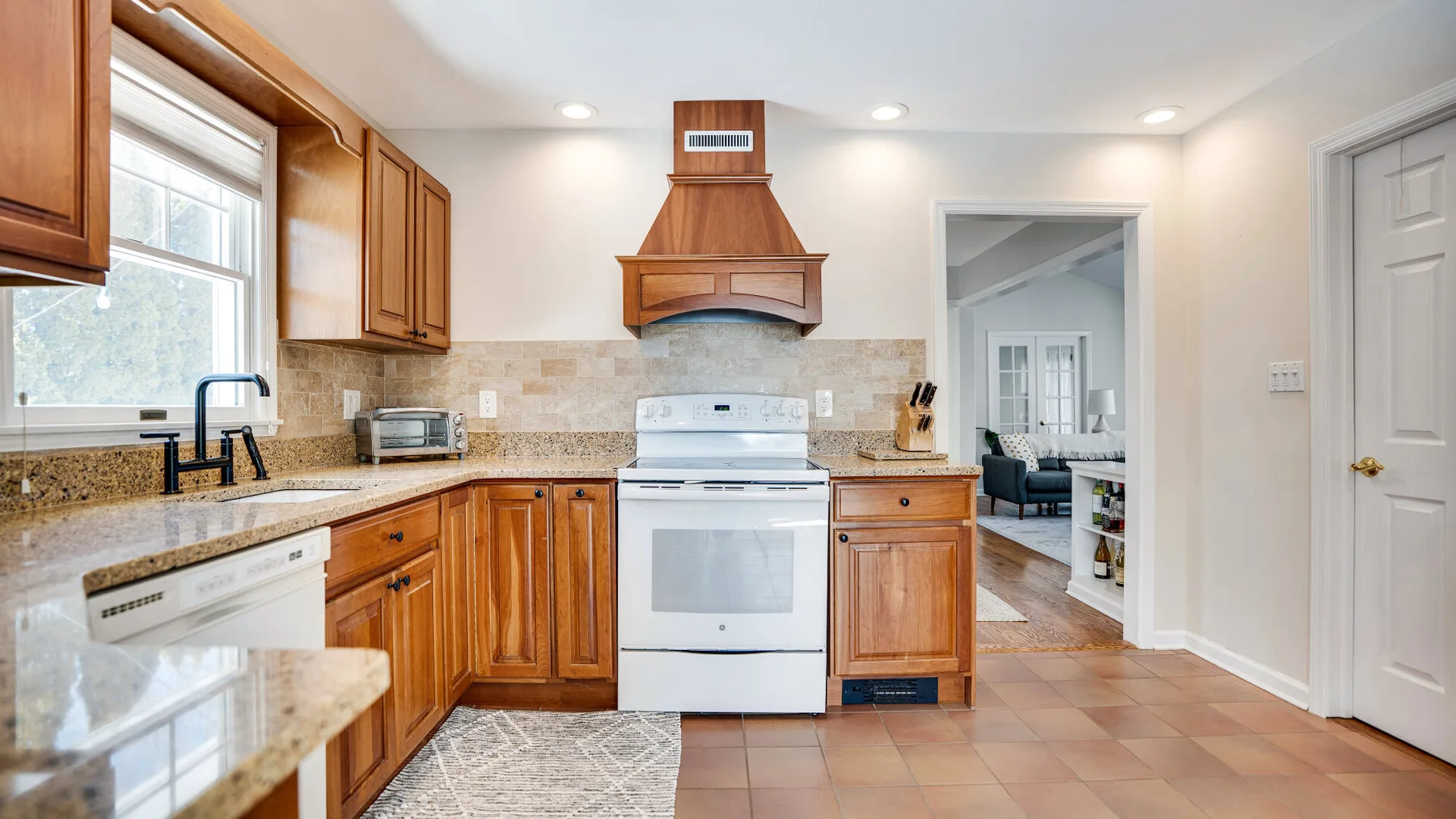 Una cocina con gabinetes de madera, una estufa central y una encimera junto a una ventana.