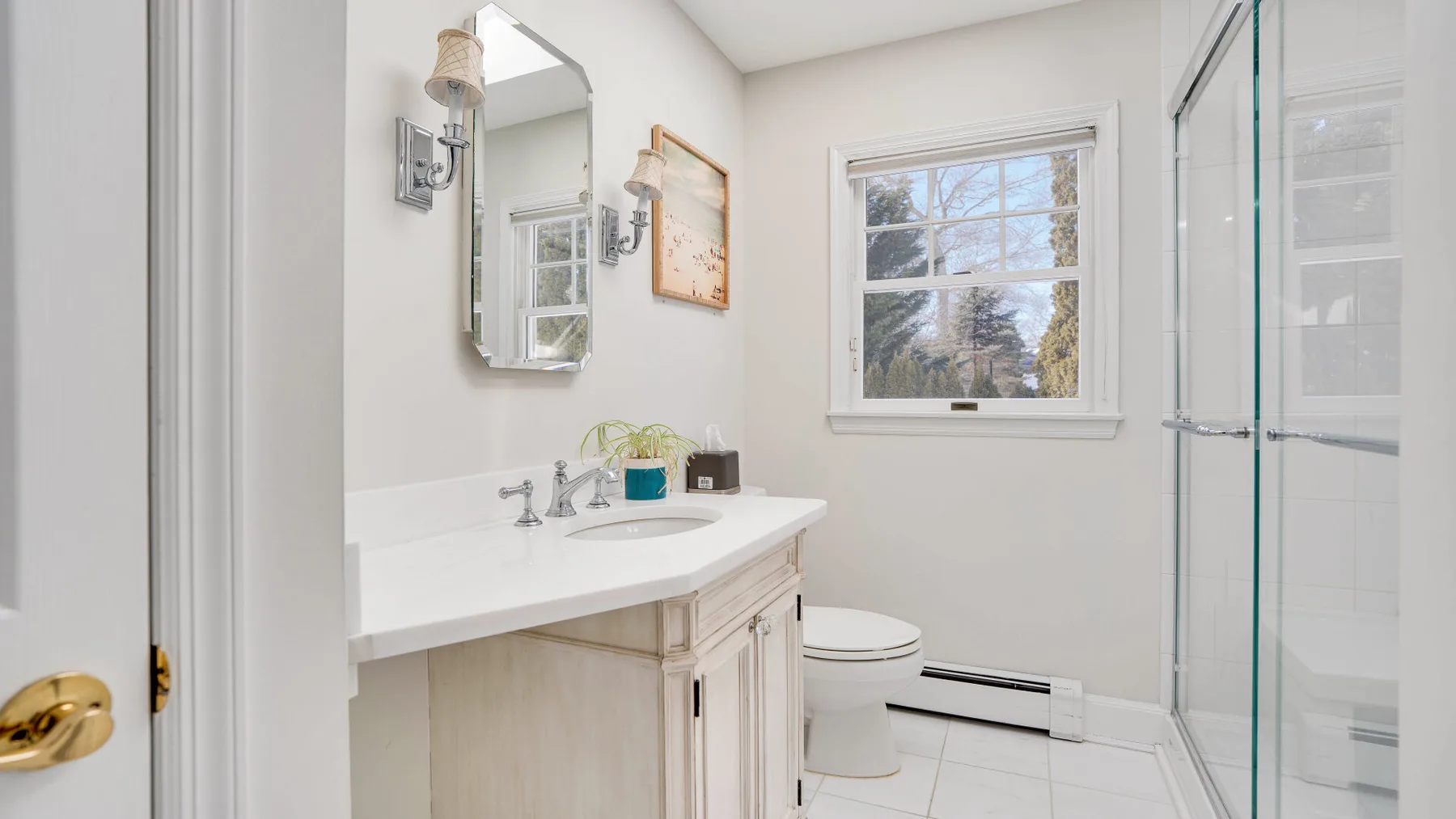 Un baño luminoso con lavabo, inodoro y ducha de vidrio.