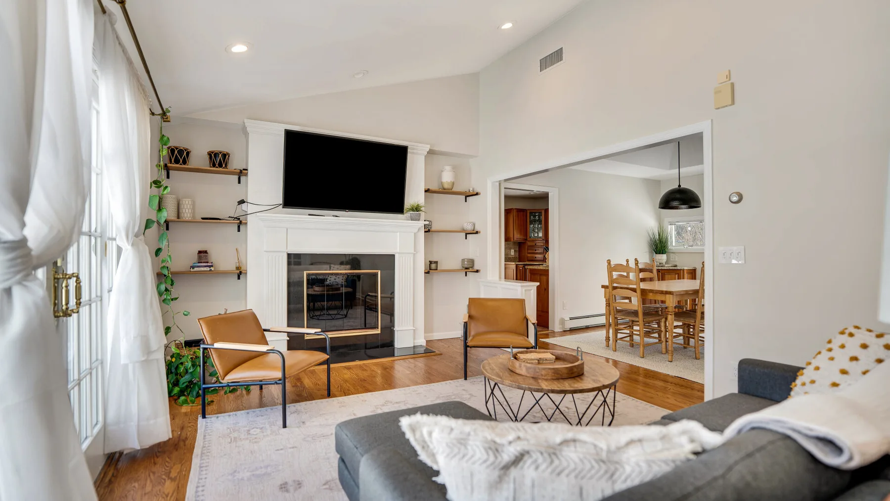 Una sala luminosa con chimenea, televisor y asientos junto a un comedor.