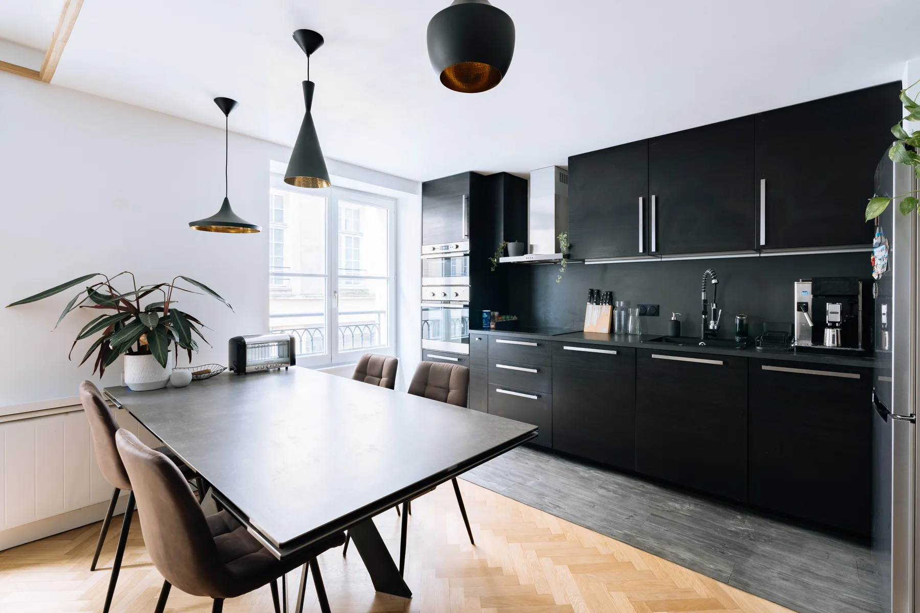 A modern kitchen and dining area with dark cabinetry and a large table.