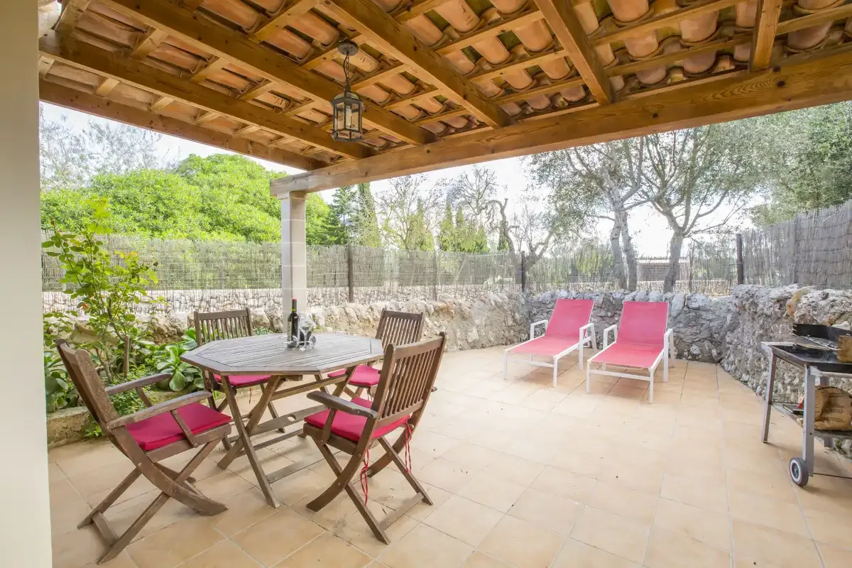 A covered outdoor patio has a dining table and chairs beside two lounge chairs.