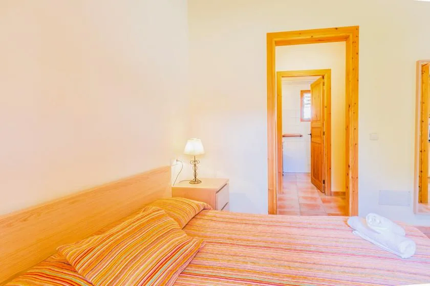 A bedroom with a striped bedspread and an open doorway to another room.