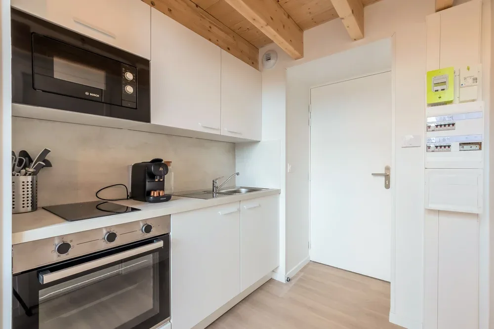 A compact kitchen with white cabinets, a countertop, and built-in appliances.